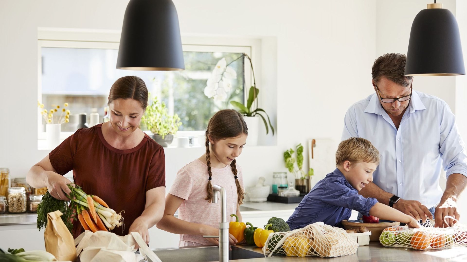 Parents and children unpacking grocery in kitchen