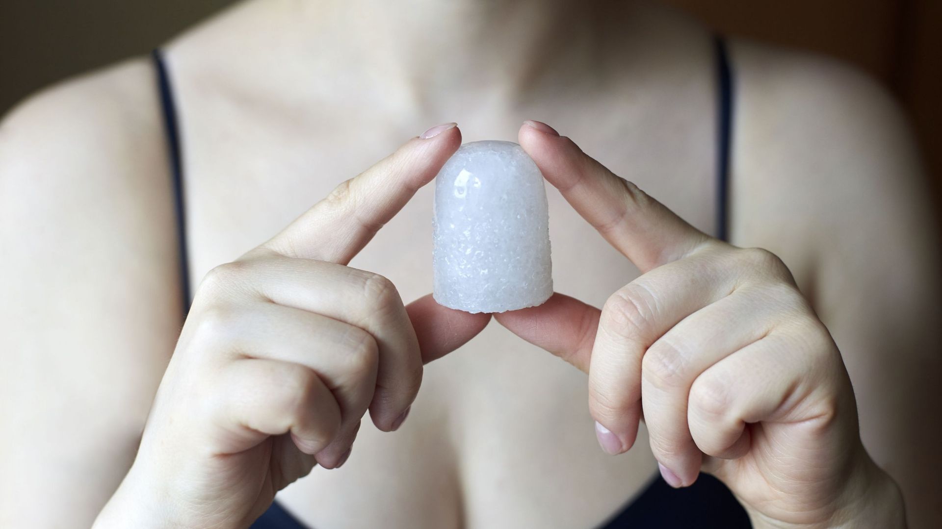 A woman holding a natural deodorant - alunite crystal
