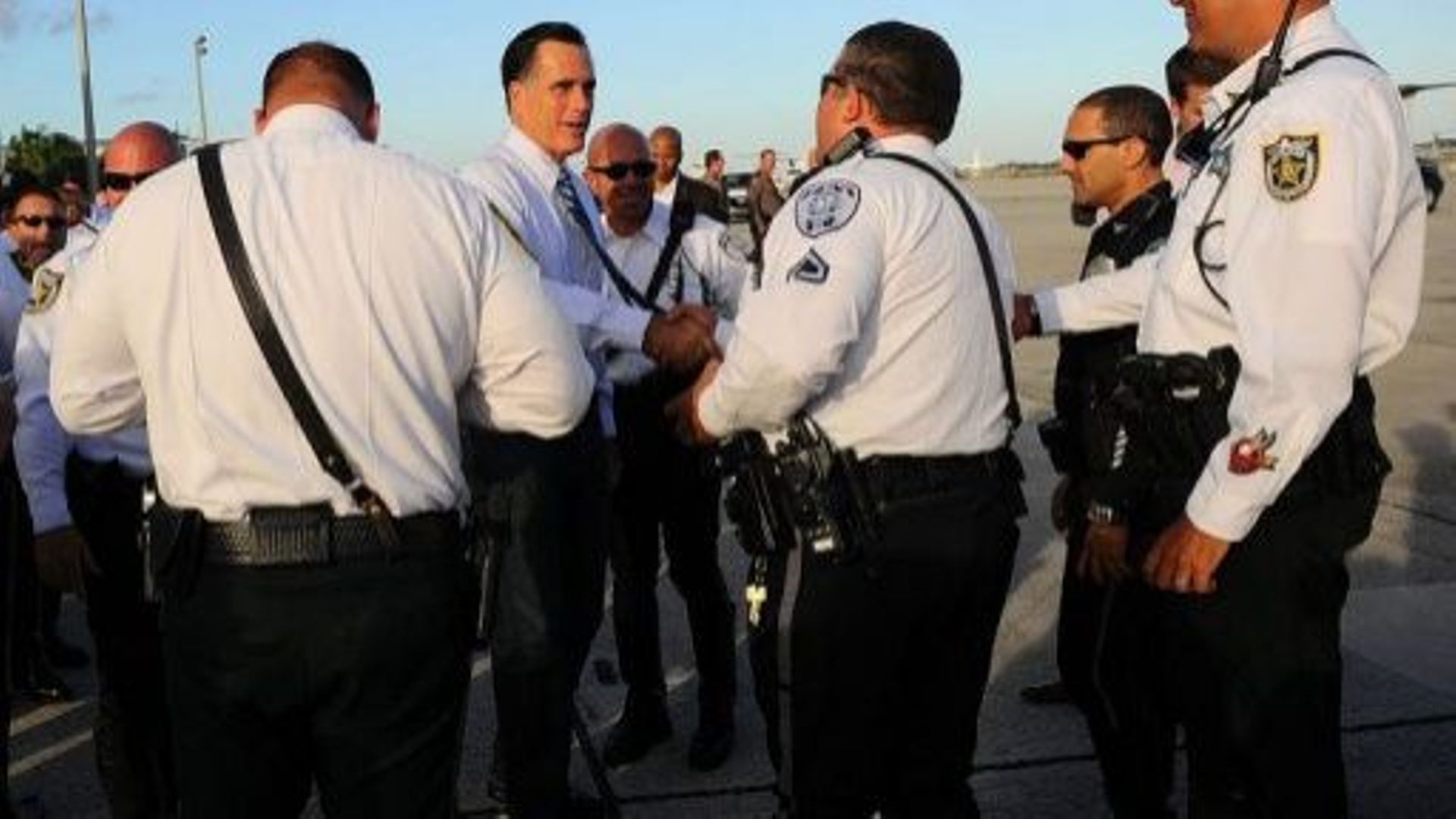 Mitt Romney, candidat à l'élection présidentielle, salue des policiers avant d'embarquer dans un avion, le 23 octobre 2012 à West palm Beach, en Floride