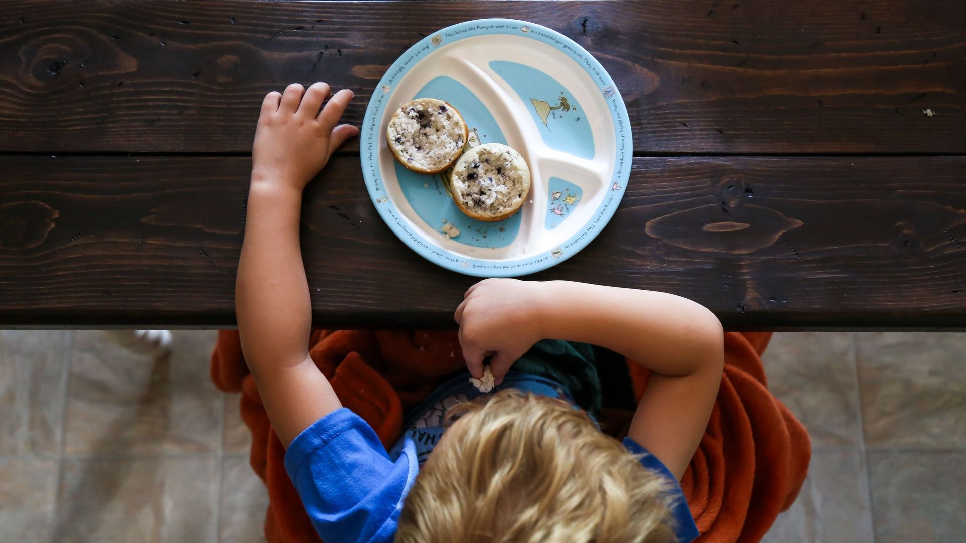 High Angle View Of Boy Eating Bread While Sitting On Table At Home