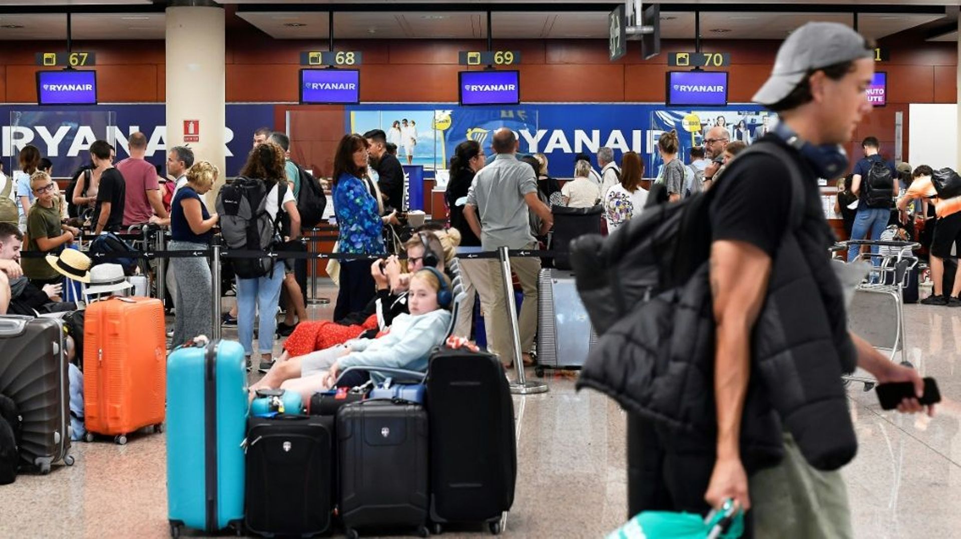 Des voyageurs attendent devant les comptoirs d’enregistrement de la compagnie aérienne Ryanair, le 1er juillet 2022 à Barcelone