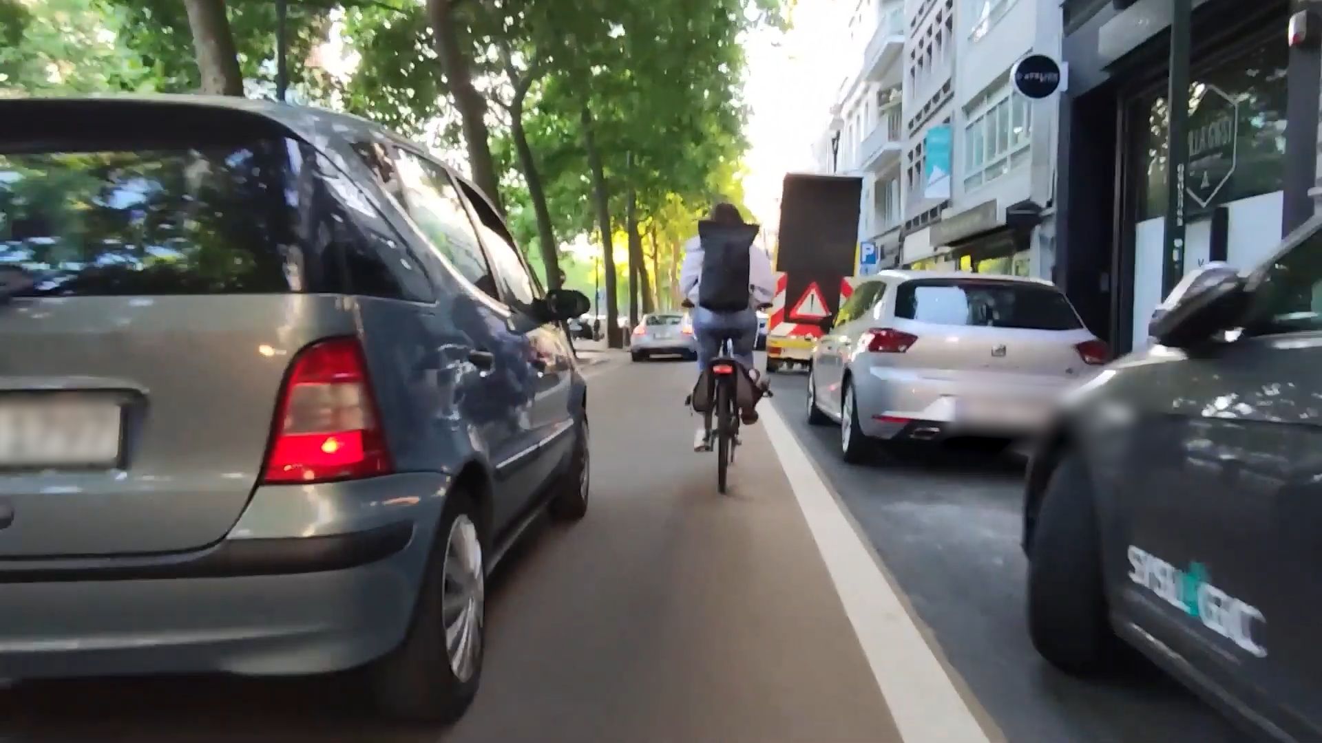 Un automobiliste dépasse un cycliste dans une rue étroite