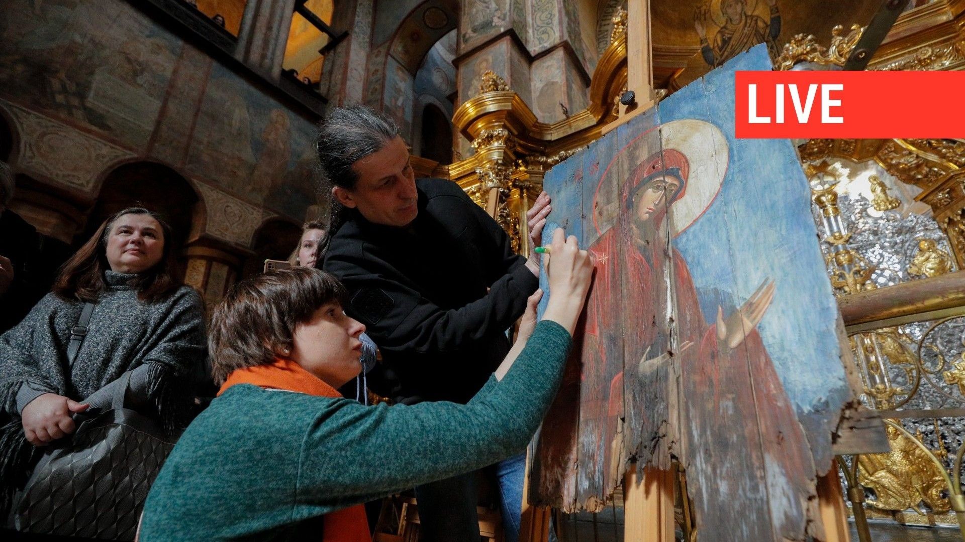 Les artistes Sonya Atlantova et Oleksandr Klymenko écrivent les noms des combattants ukrainiens tombés au combat sur une œuvre d'art lors de l'exposition "Sophia deisis" à la cathédrale Sainte-Sophie de Kiev, en Ukraine, le 22 avril 2023.