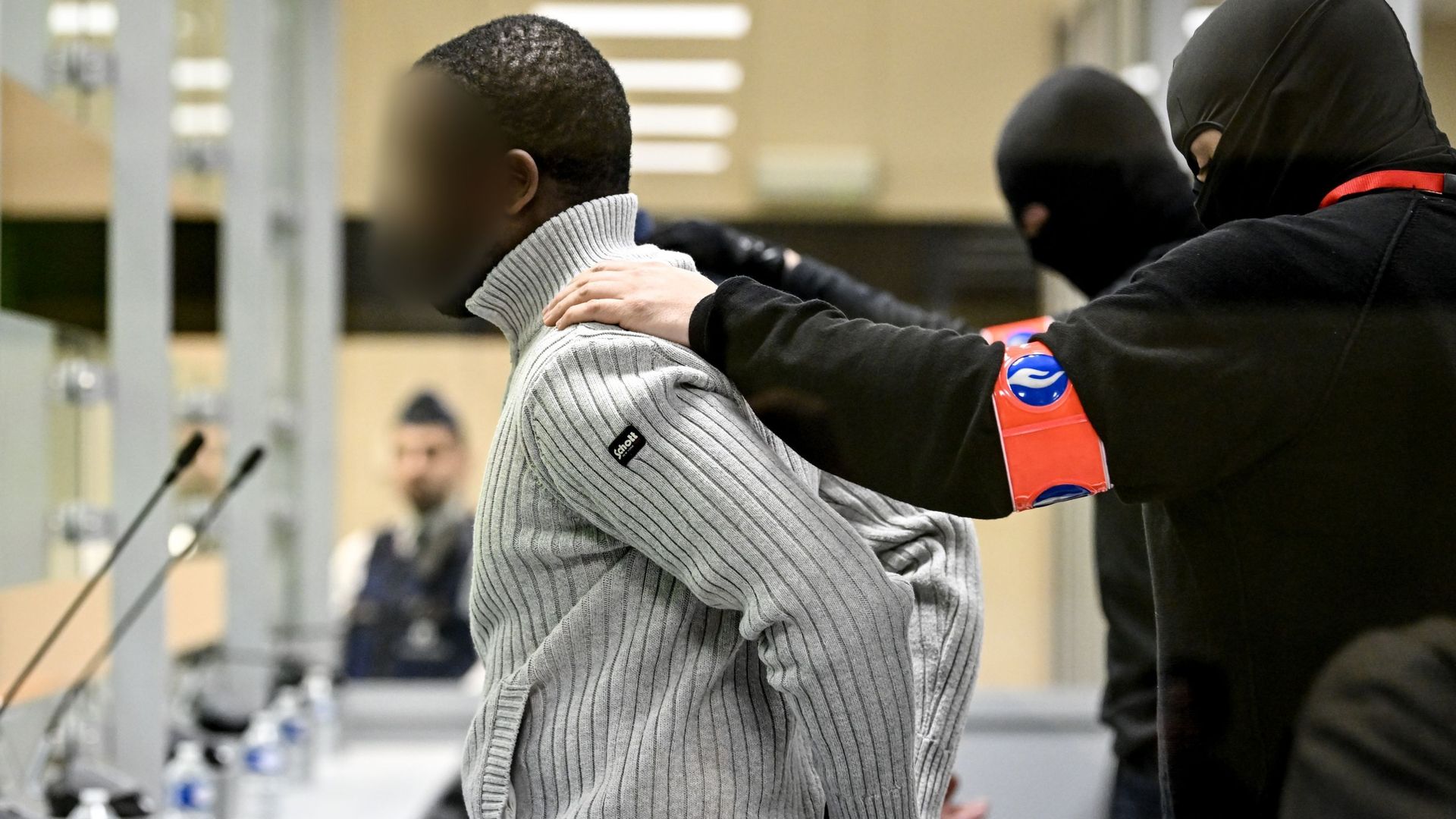 Policiers cagoulés qui escortent les accusés du procès des attentats de Bruxelles