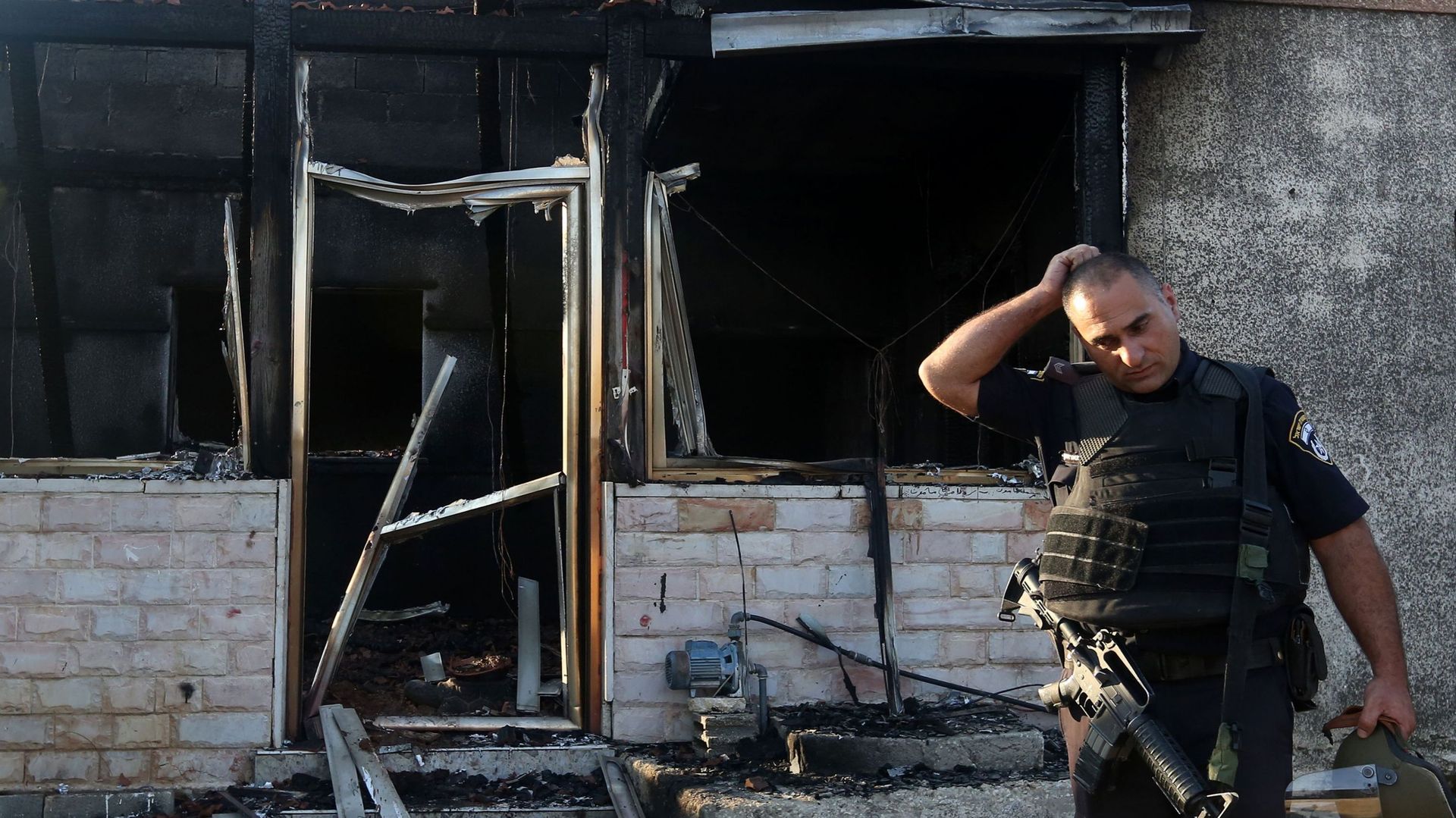 Un membre des forces de sécurité israéliennes photographié devant la maison palestinienne où le bébé Ali Dawabcheh, 18 mois, a été brûlé vif par des extrémistes israéliens.