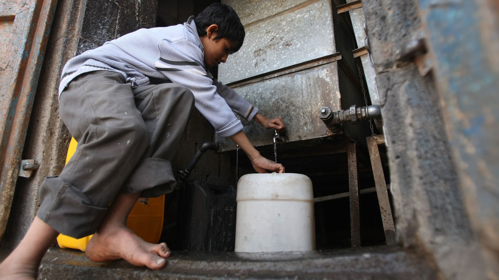 Un jeune yéménite remplit des conteneurs d'eau à partir d'un robinet public à Sanaa alors que le pays appauvri fait face à une pénurie d'eau et de carburant.