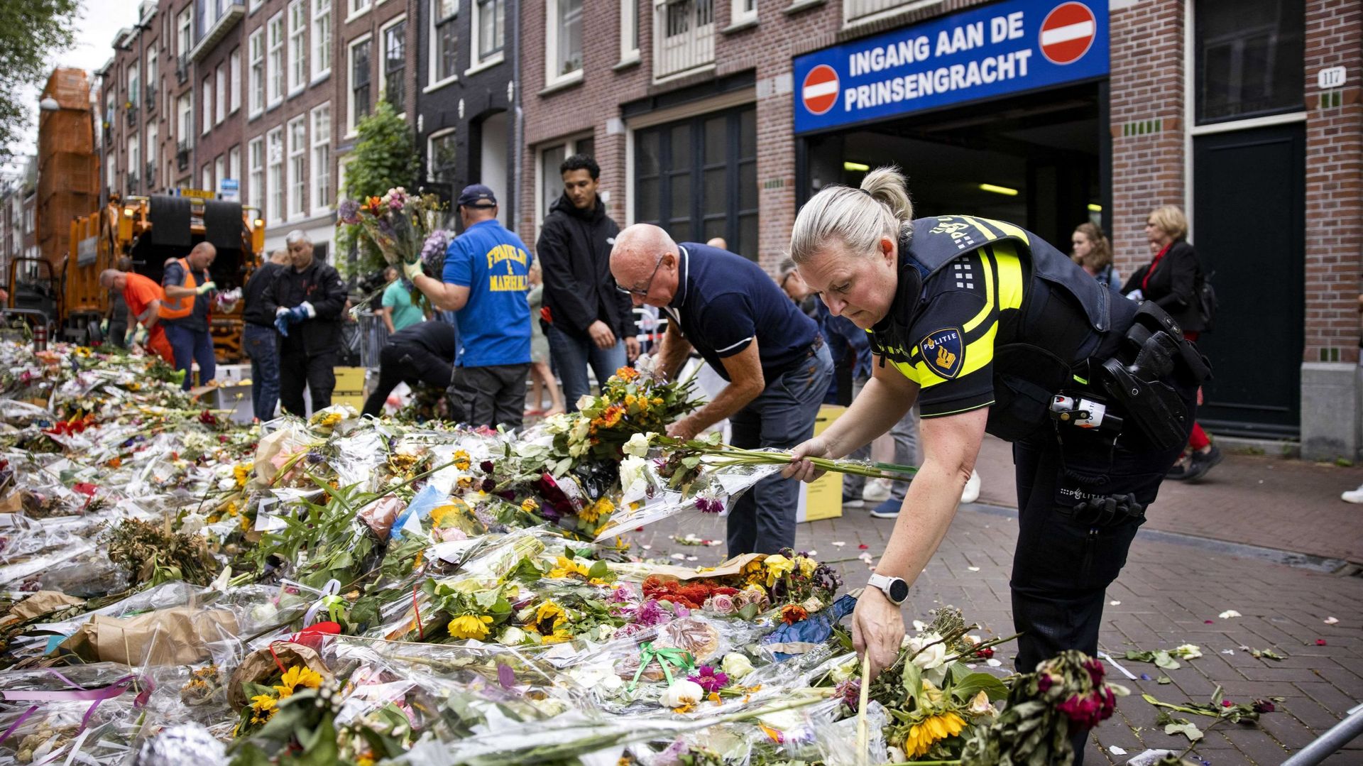 Des employés de la municipalité nettoient les fleurs et les cartes qui ont été déposées par des personnes en deuil en hommage à Peter R. de Vries dans la Lange Leidsedwarsstraat à Amsterdam, le 23 juillet 2021.