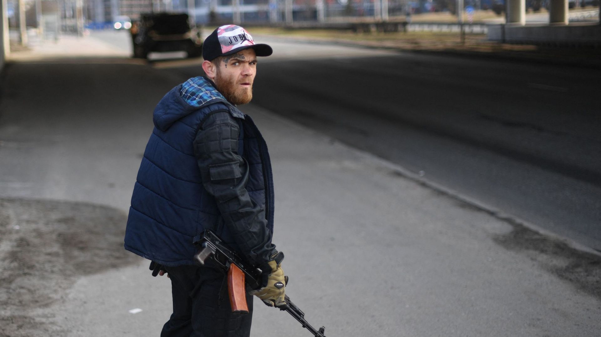 Un volontaire, tenant un fusil, protège une route principale menant à Kiev, le 25 février 2022.