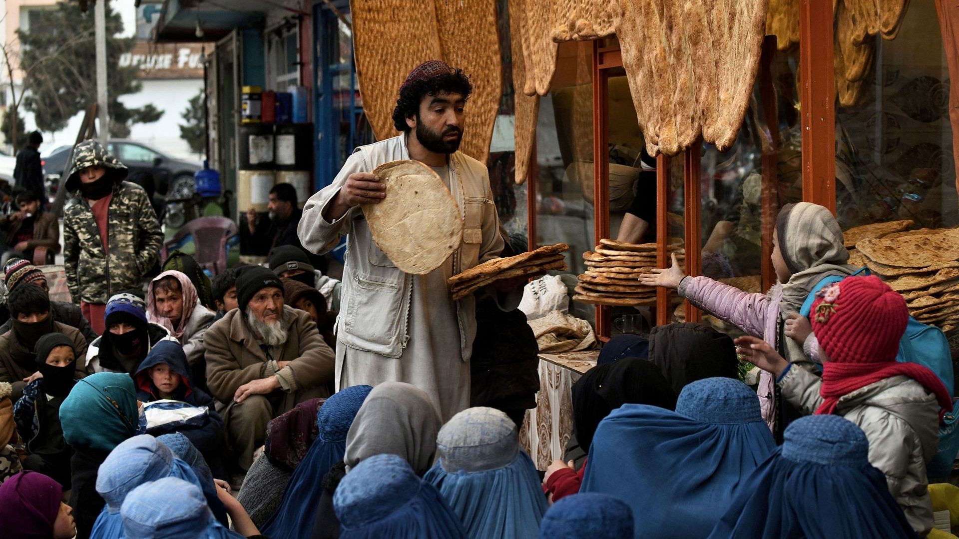 Un Afghan distribue du pain aux personnes dans le besoin devant un restaurant à Kaboul, le 19 février 2022.