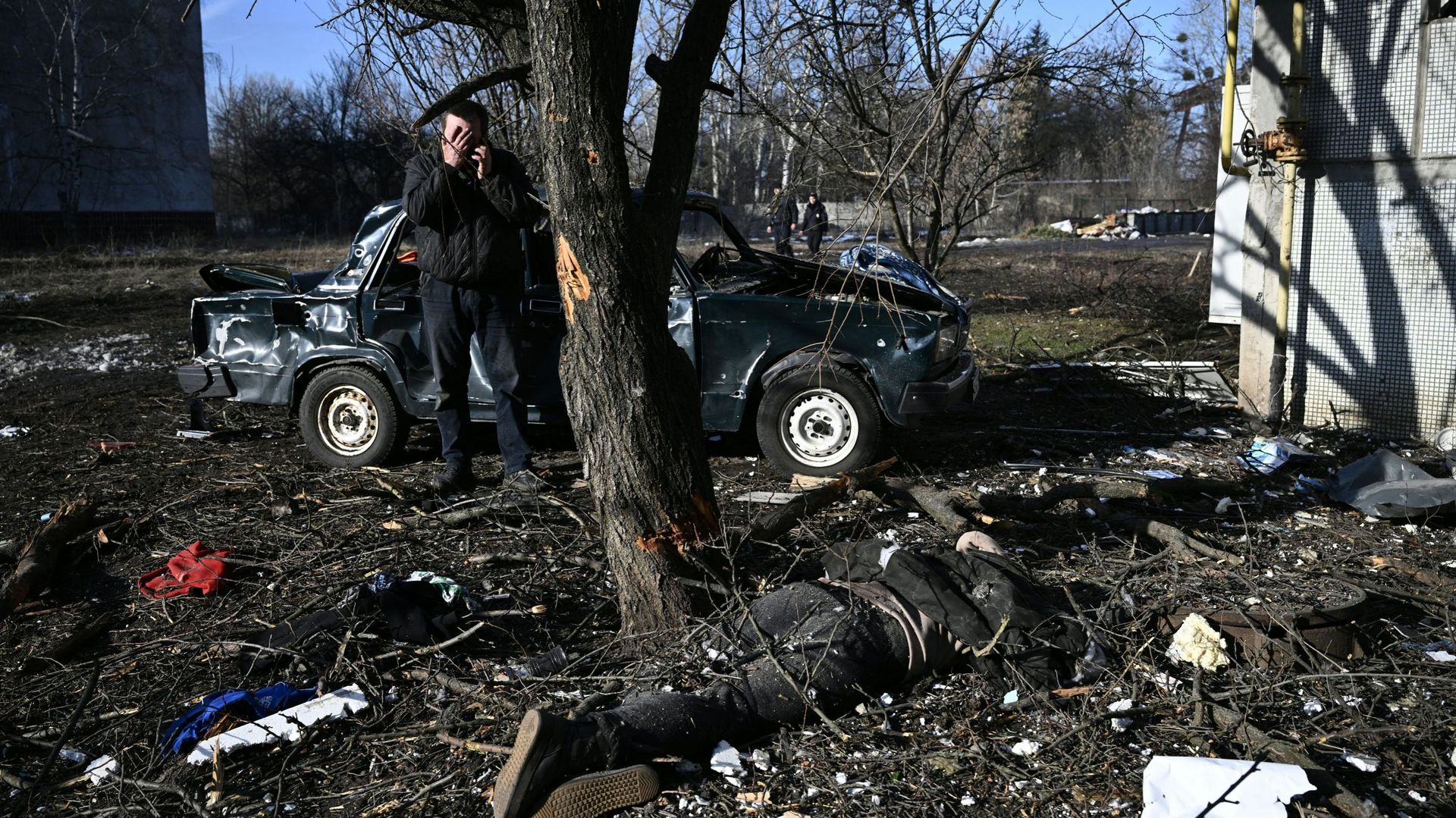 Un homme réagit alors qu'il se tient à côté d'un corps allongé sur le sol après les bombardements sur la ville de Chuguiv, dans l'est de l'Ukraine, le 24 février 2022.