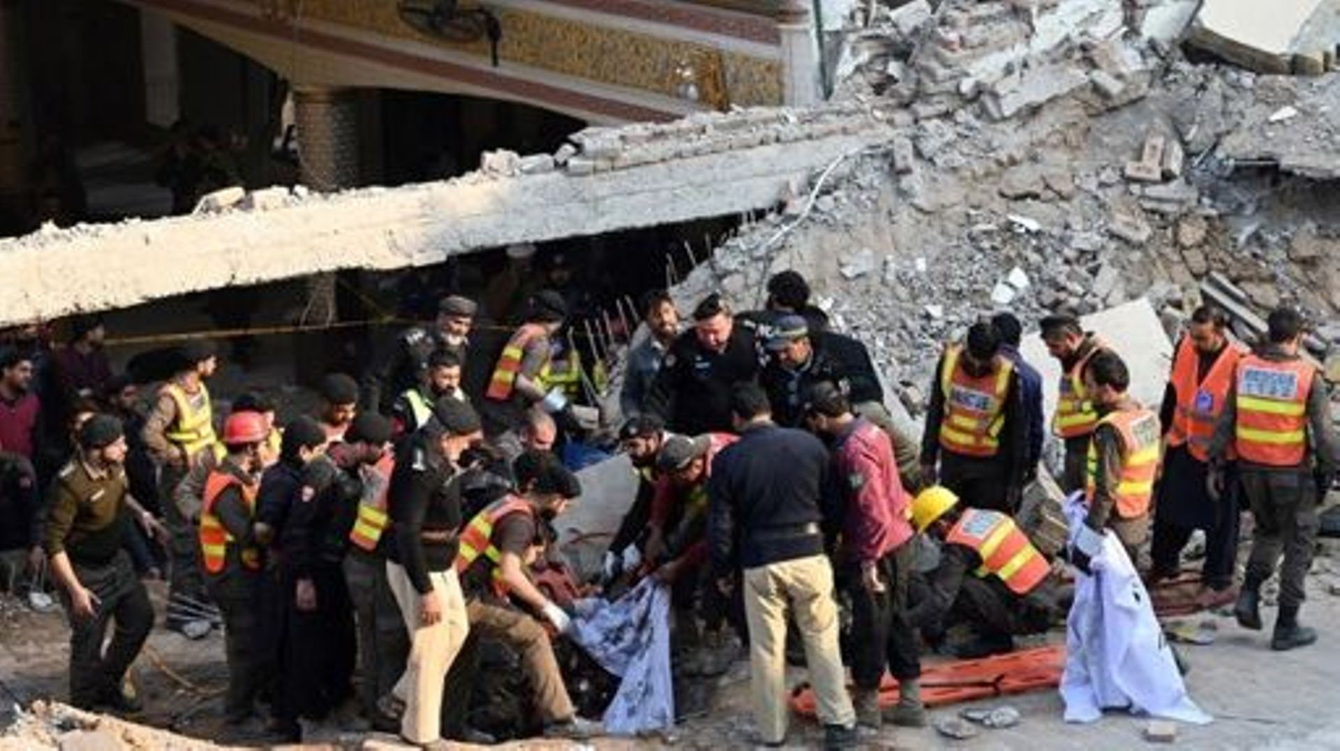 Rescue workers carry the remains of the blast victims from the debris of a damaged mosque after a blast inside the police headquarters in Peshawar on January 30, 2023.  A blast at a mosque inside a police headquarters in Pakistan on January 30 killed at l