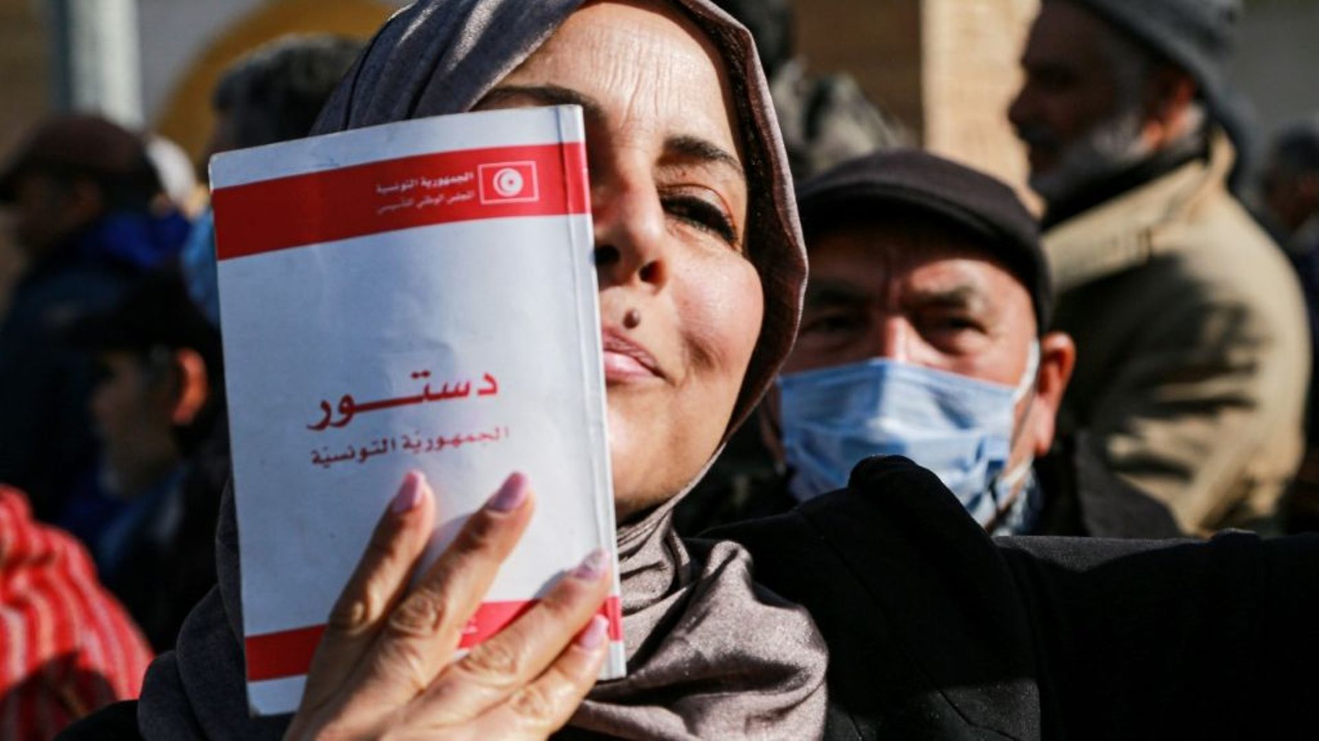 Une manifestante brandissant une copie de la Constitution tunisienne lors d’un rassemblement à Tunis, le 13 février 2022