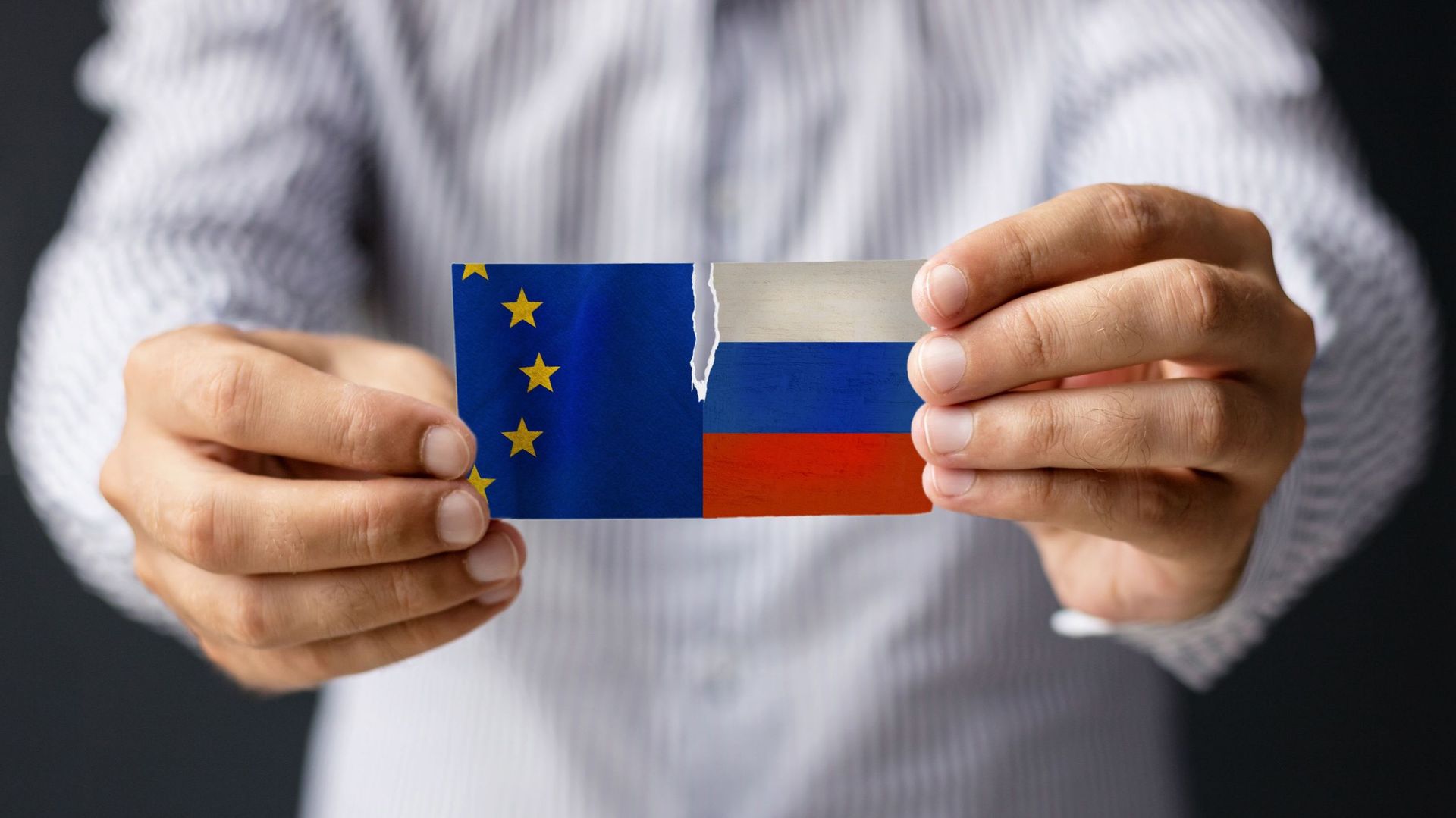 European Union Vs Russia. Close-Up Of Man Holding Eu And Russian Flag.