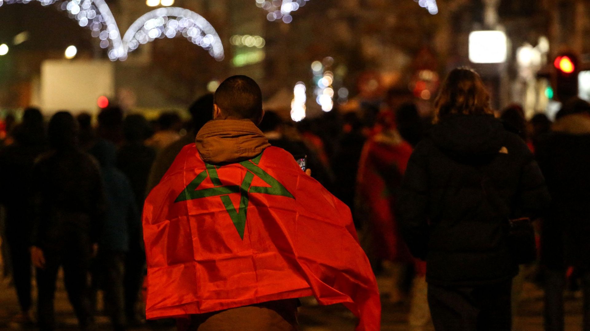 Un supporter, enveloppé dans le drapeau marocain dans une rue après la victoire du Maroc lors du match de football du groupe F de la Coupe du monde Qatar 2022 entre le Maroc et le Canada, à Bruxelles, le 1er décembre 2022.
