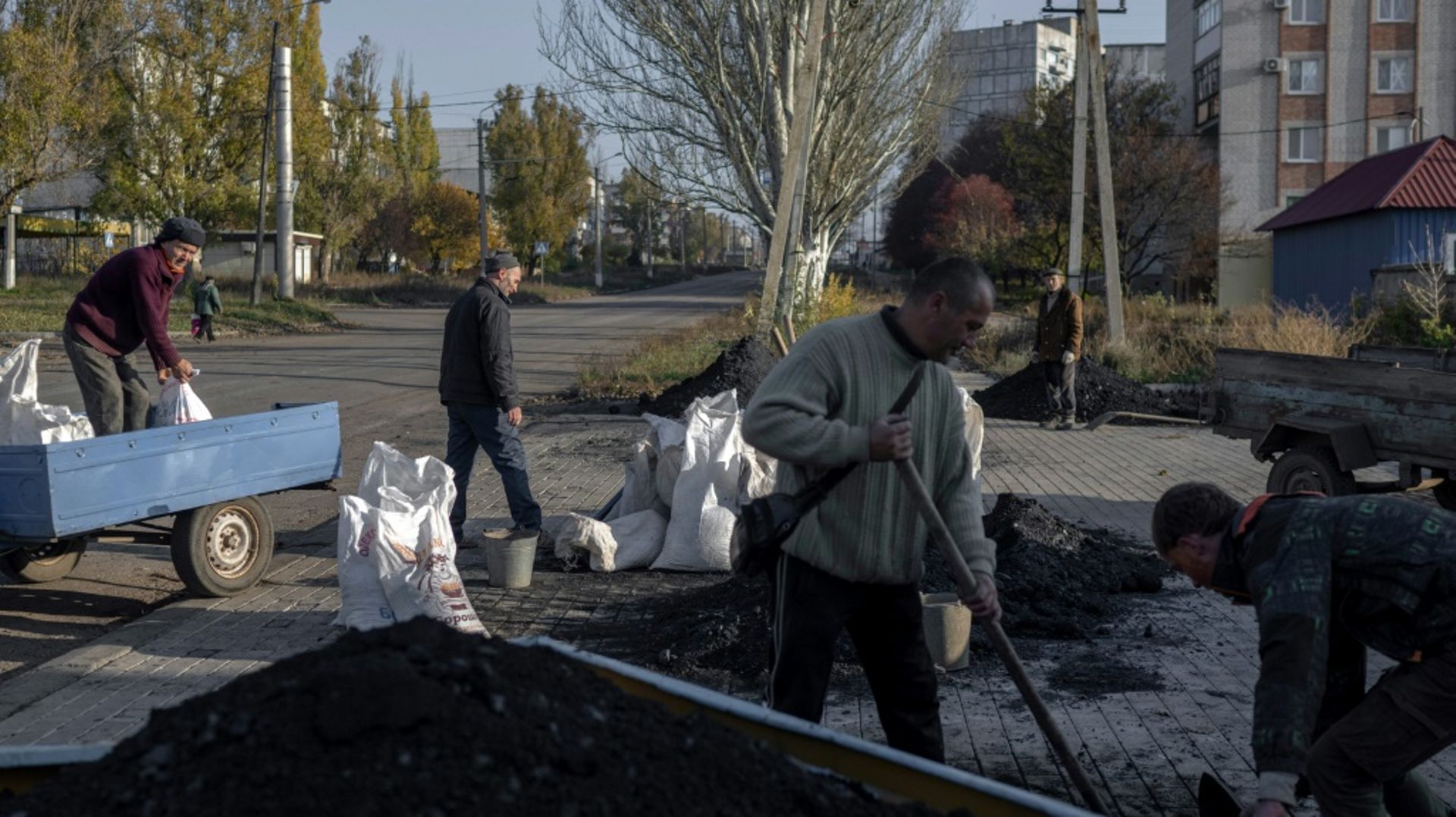 Des hommes remplissent de charbon une carriole pour le distribuer aux habitants avant l’arrivée de l’hiver, dans la périphérie de Bakhmout, le 9 novembre 2022 en Ukraine.