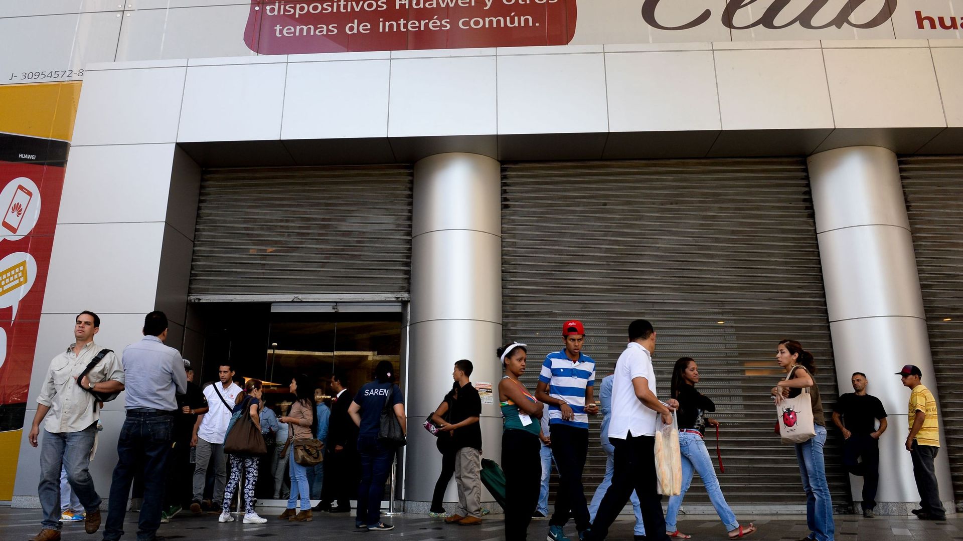 Des habitants de Caracas attendent à l'extérieur d'un centre commercial fermé. Les centres commerciaux doivent réduire leurs horaires d'ouverture suite aux récentes mesures.
