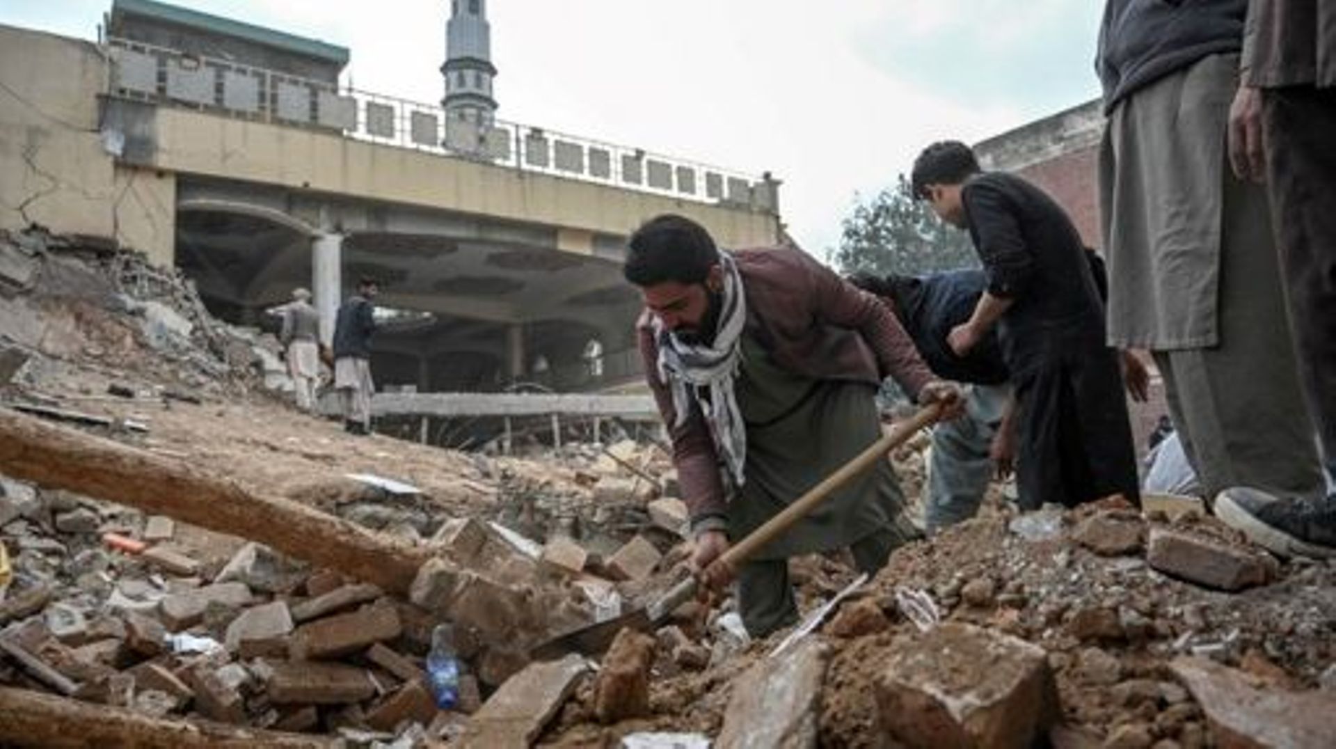 Plain-clothed policemen and labourers remove debris beside a damaged mosque following January's 30 suicide blast inside the police headquarters in Peshawar on February 1, 2023.  A suicide blast at a mosque inside a Pakistan police headquarters was a targe