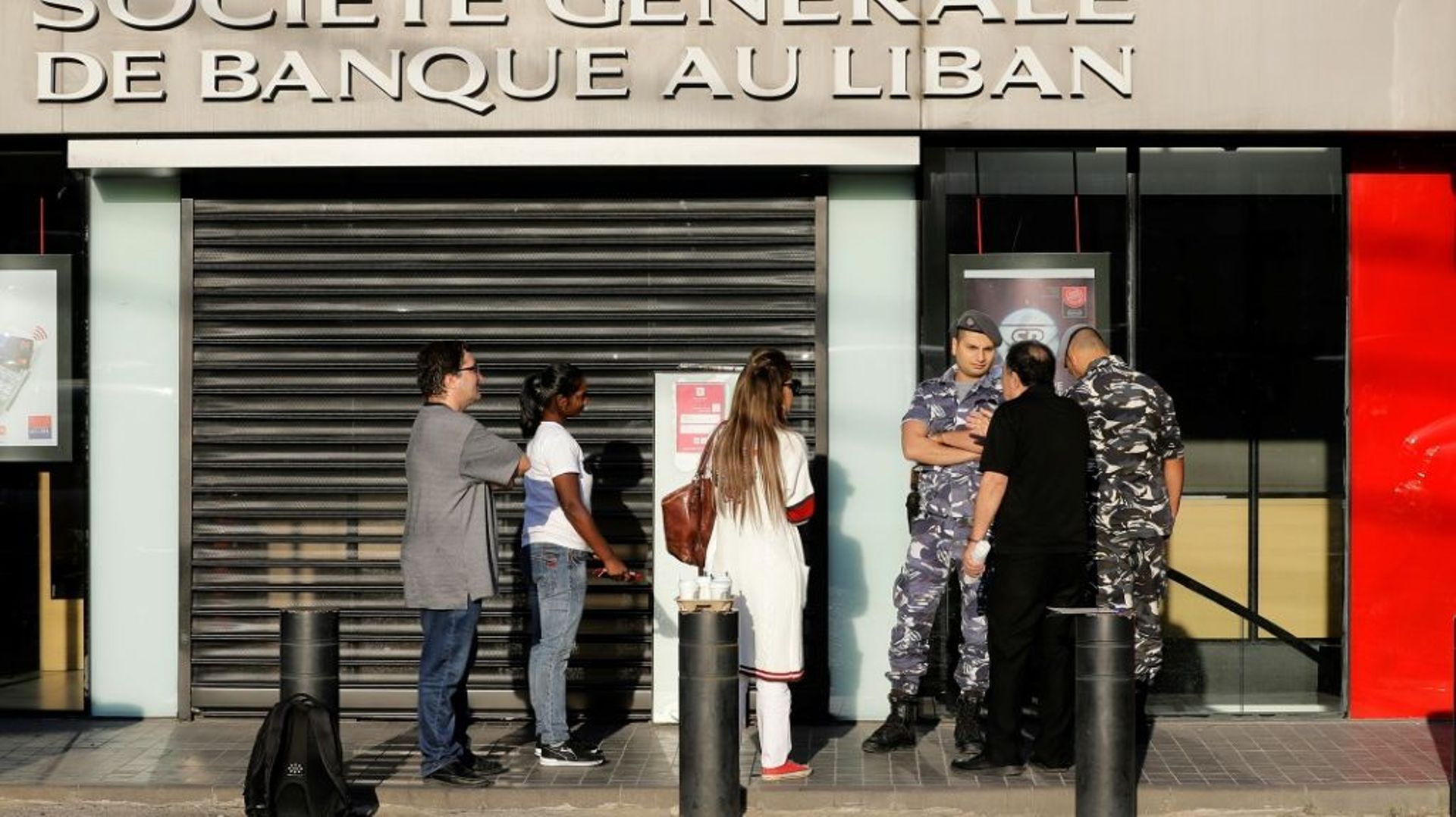 Des membres des forces de l'ordre contrôlant l'entrée d'une succursale d'une banque à Beyrouth, le 19 novembre 2019