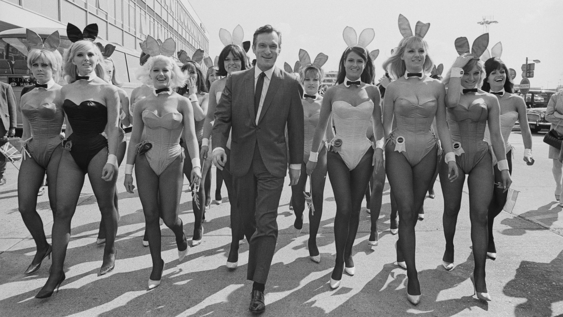 Le créateur de Playboy, Hugh Hefner (1926-2017), en compagnie d’un groupe de playmates à l’aéroport de Londres (aujourd’hui Heathrow), le 25 juin 1966. Hefner est arrivé en avion pour l’ouverture du Playboy Club de Londres.