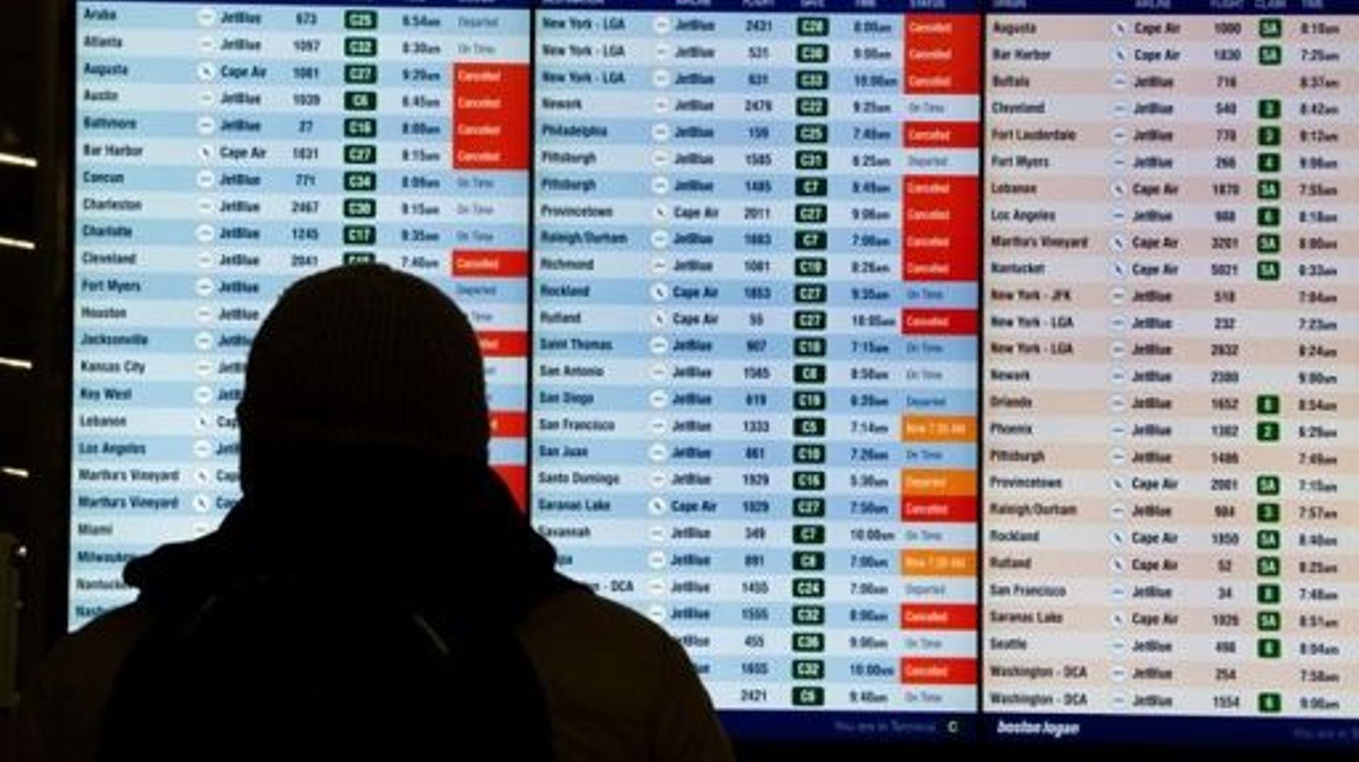 Des voyageurs vérifient si des vols ont été annulés à l'aéroport international Logan de Boston, dans le Massachusetts, le 23 décembre 2022.  