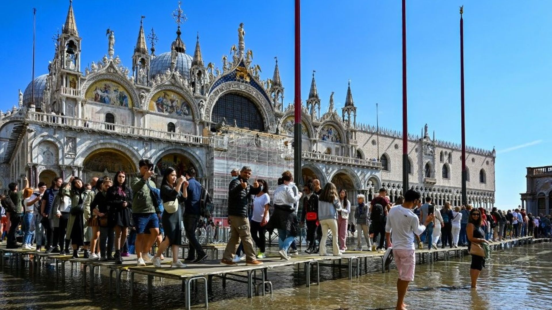 Des touristes marchent sur des passerelles installées sur la place Saint-Marc à Venise, le 27 septembre 2022.