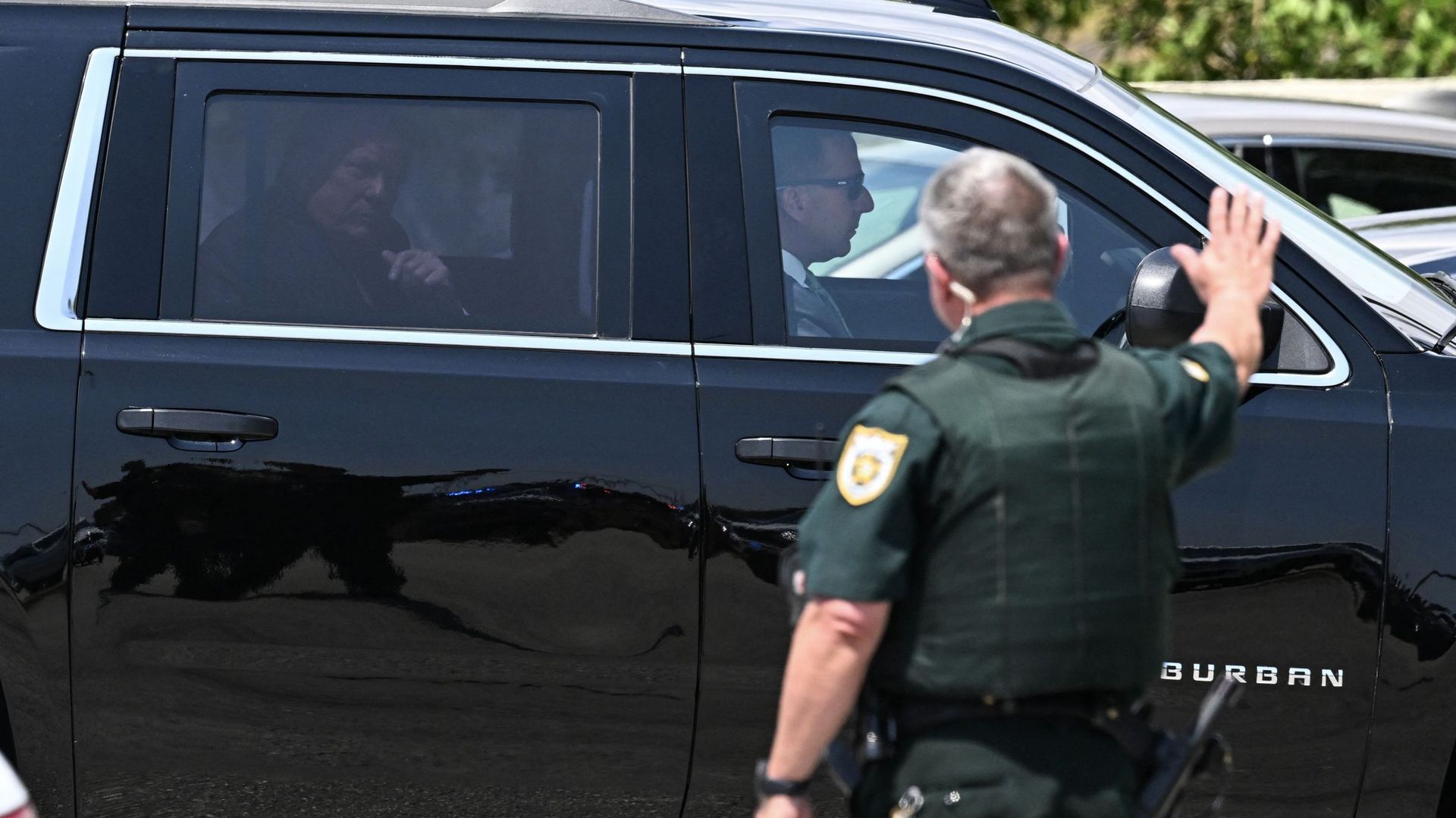 Un policier salue l'ancien président américain Donald Trump à son arrivée à l'aéroport international de Palm Beach à West Palm Beach, en Floride, ce 3 avril 2023.