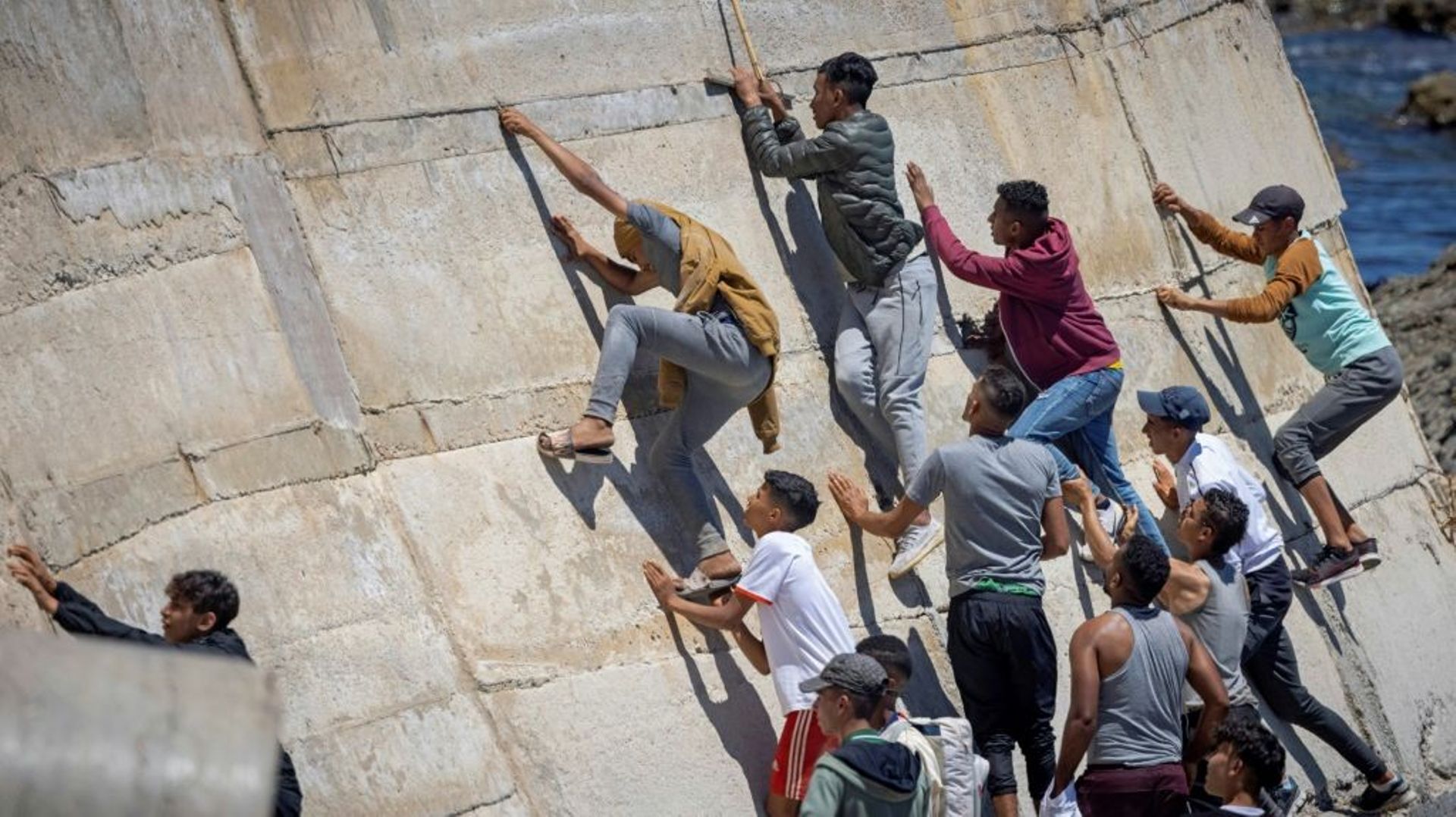 Des migrants escaladent un mur pour atteindre l’enclave espagnole de Ceuta, le 19 mai 2021