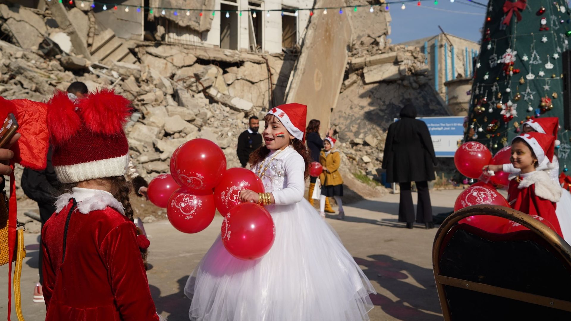 Des enfants s’amusent lors des célébrations du Nouvel An devant des débris de bâtiments à Mossoul, en Irak, le 30 décembre 2021.