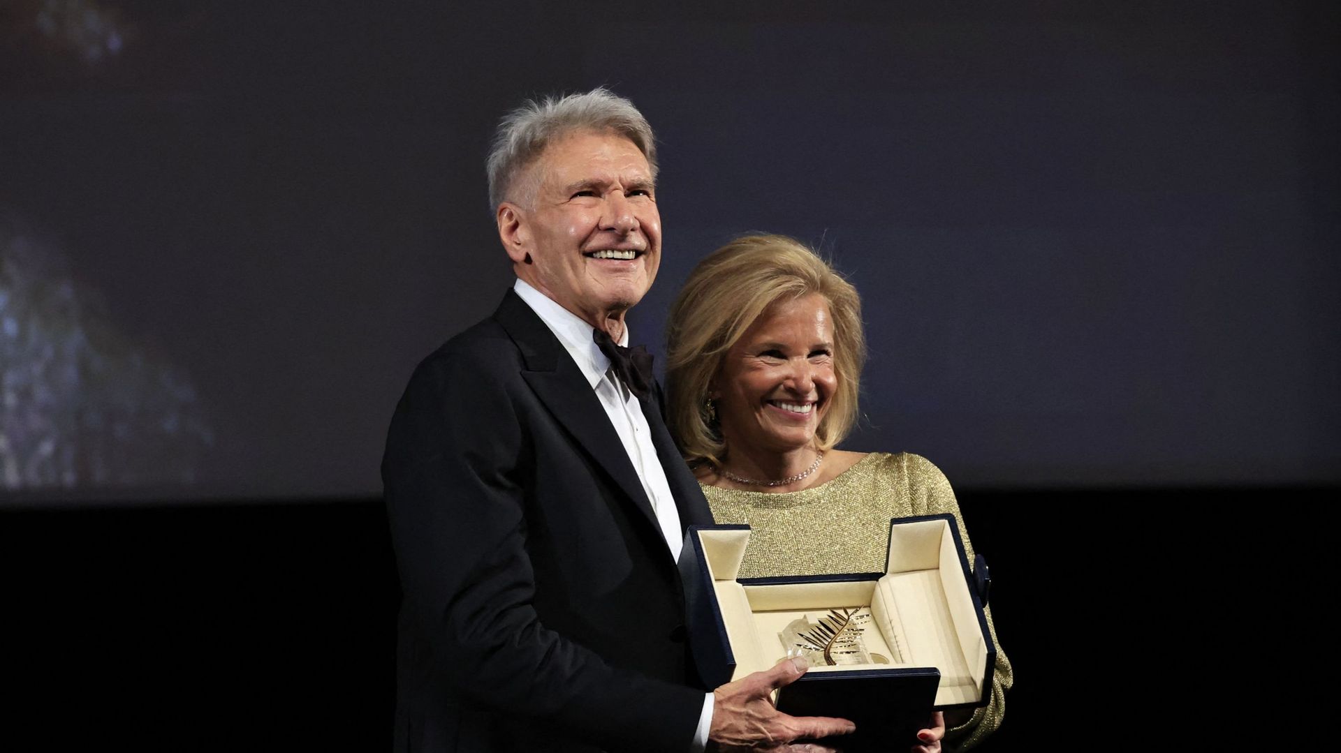 L'acteur américain Harrison Ford pose sur scène avec la directrice française du festival de Cannes, Iris Knobloch, après avoir reçu une Palme d'or honorifique avant la projection du film "Indiana Jones et le cadran du destin" lors de la 76e édition du fes