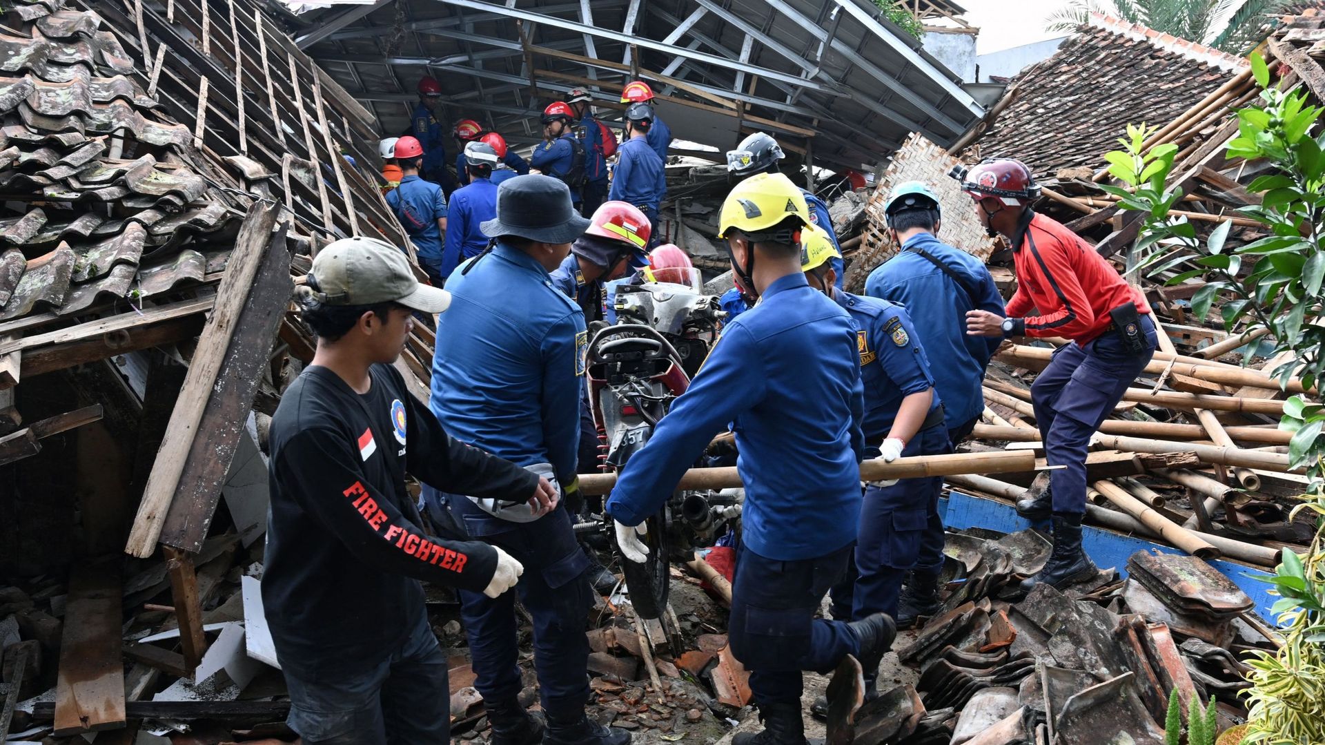 Des secouristes retirent une motocyclette alors qu’ils s’efforcent de retrouver un enfant disparu dans les décombres d’une maison effondrée à Cugenang, à Cianjur, dans l’ouest de Java, le 24 novembre 2022, à la suite d’un séisme de magnitude 5,6 survenu l