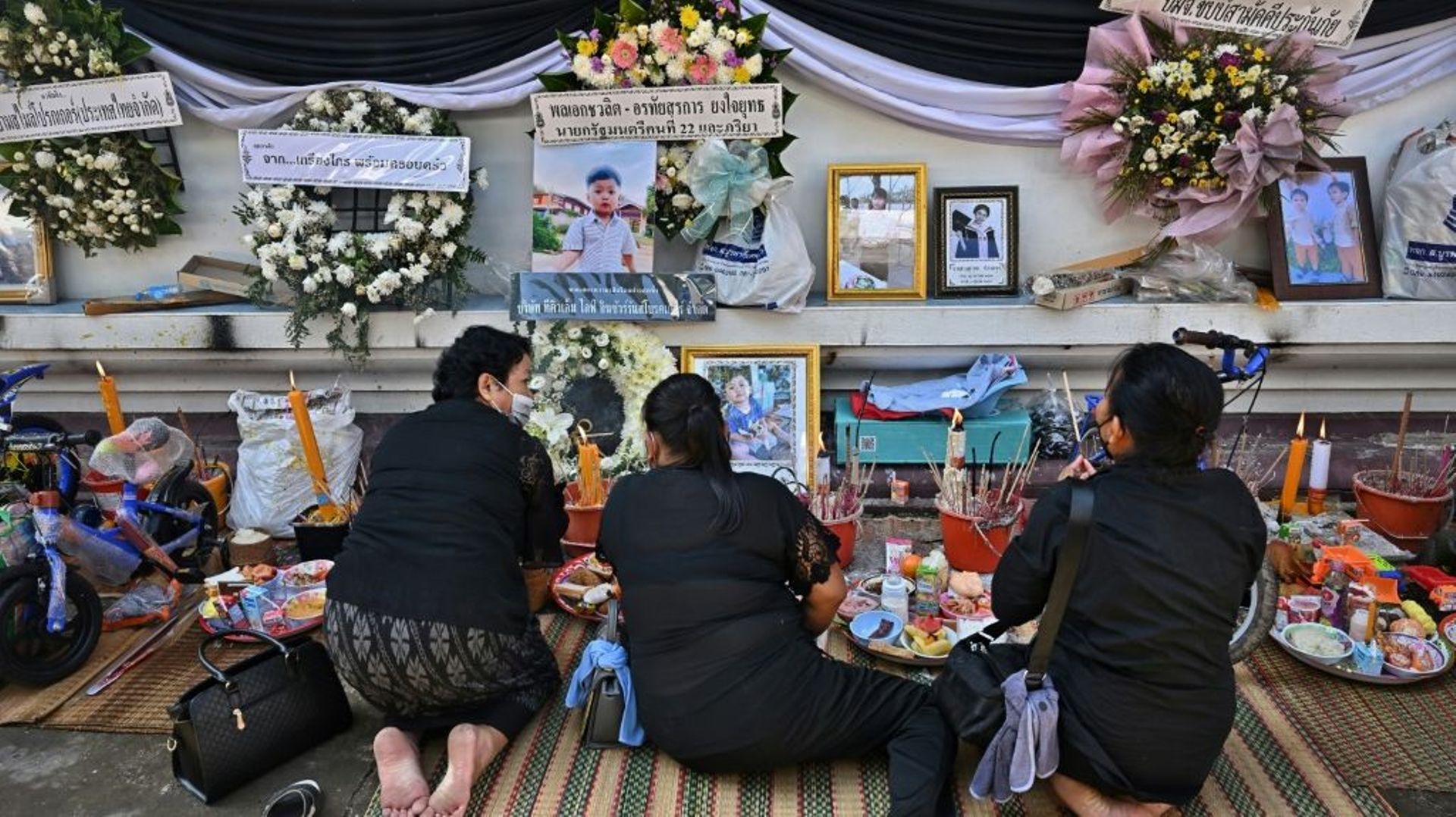 Des femmes se recueillent devant les photos des victimes d'une tuerie dans une crèche, le 11 octobre 2022 dans un temple à Nong Bua Lamphu, en Thaïlande 