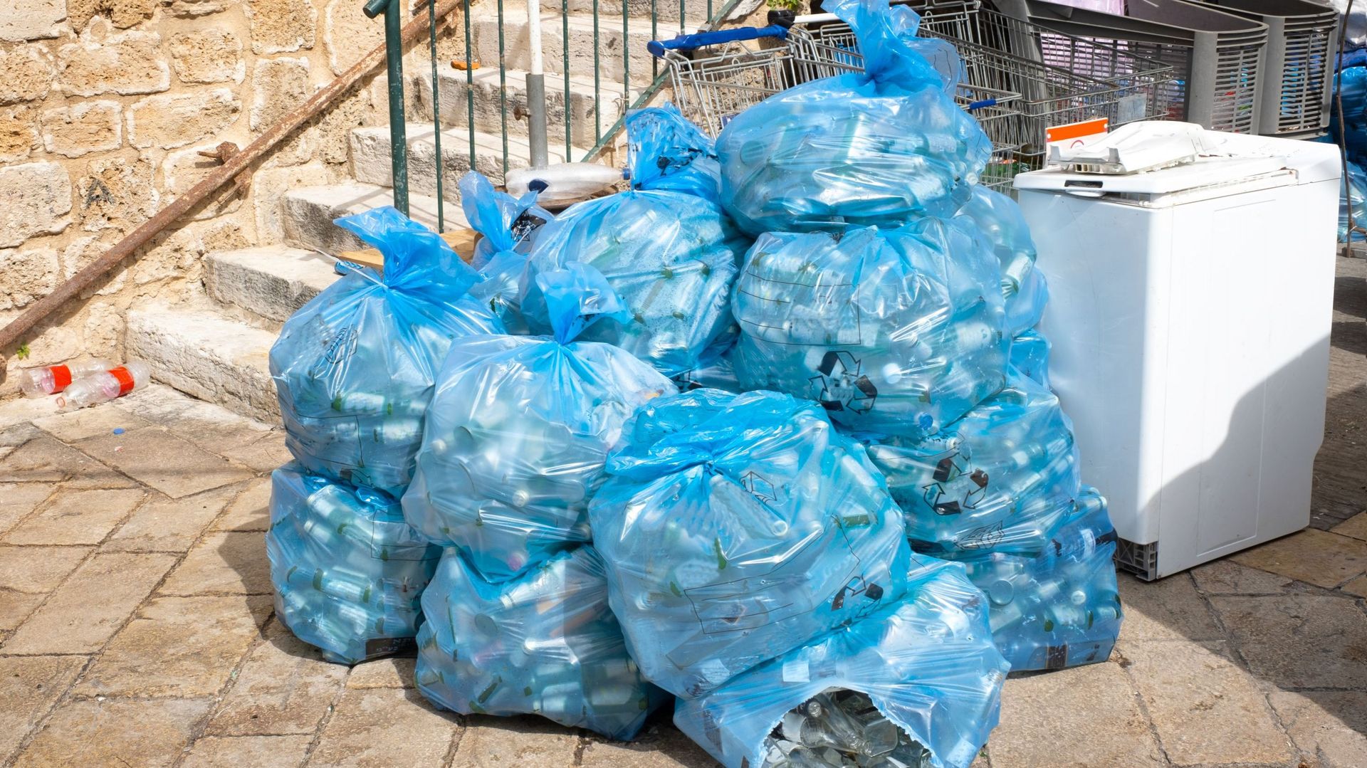 garbage in plastic blue bags on the street 