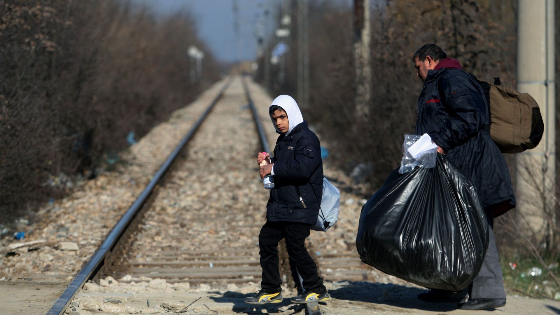 Un homme et un enfant traversent la frontière grecque vers la Macédoine