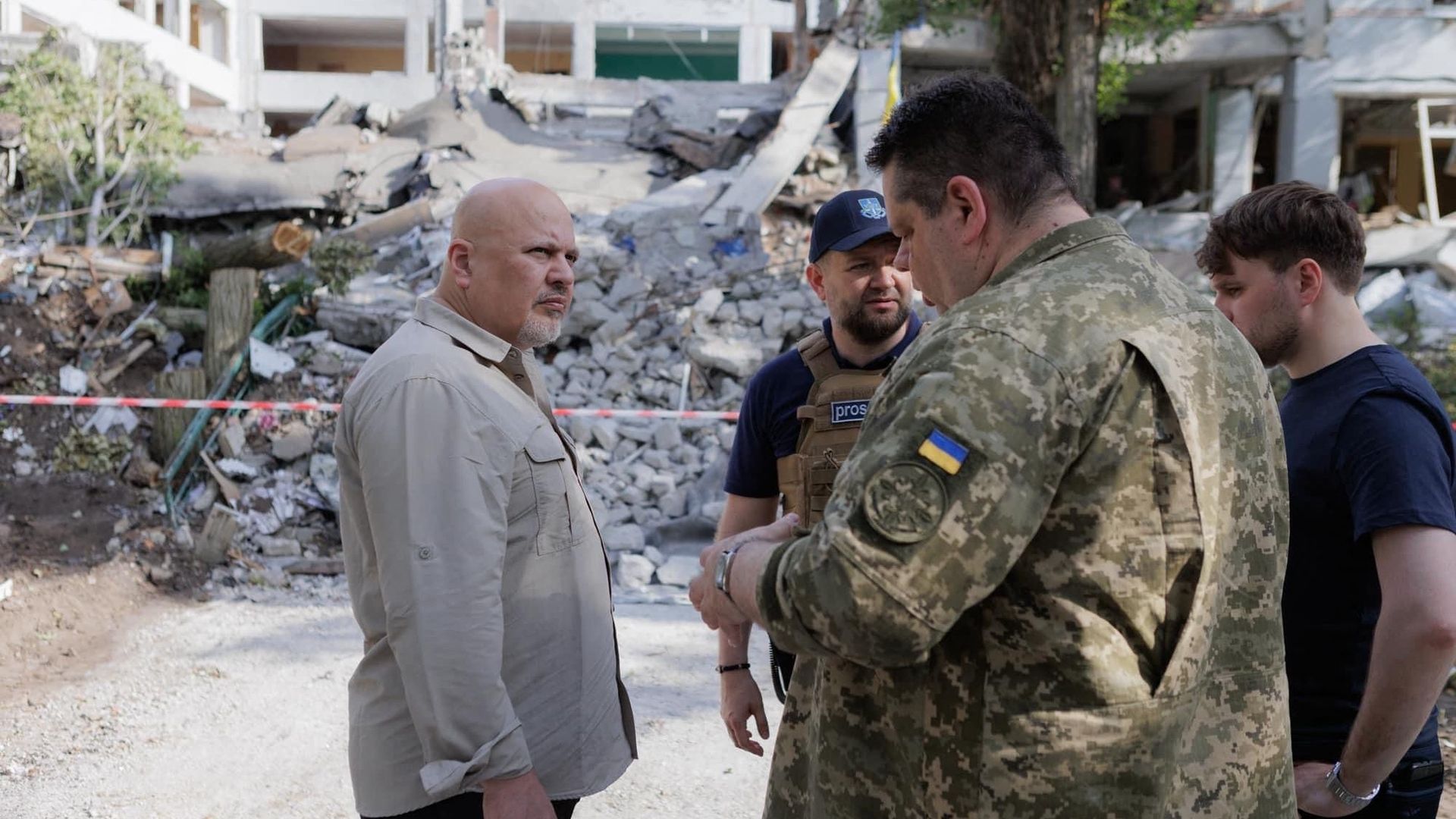 Le Procureur général de la CPI, Karim Khan, devant des décombres à Kharkiv en Ukraine, mi-juin.