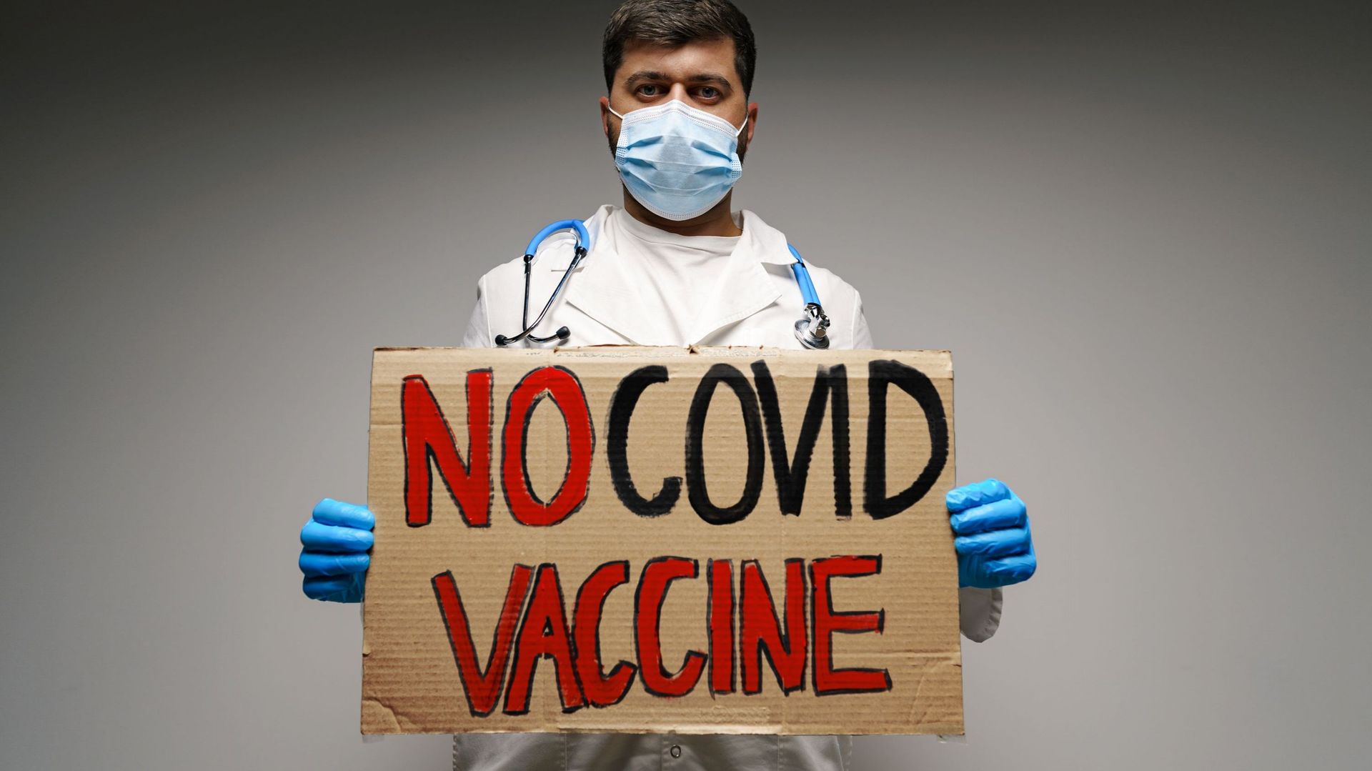Doctor holding protest banner with &#39;no COVID vaccine&#39; text