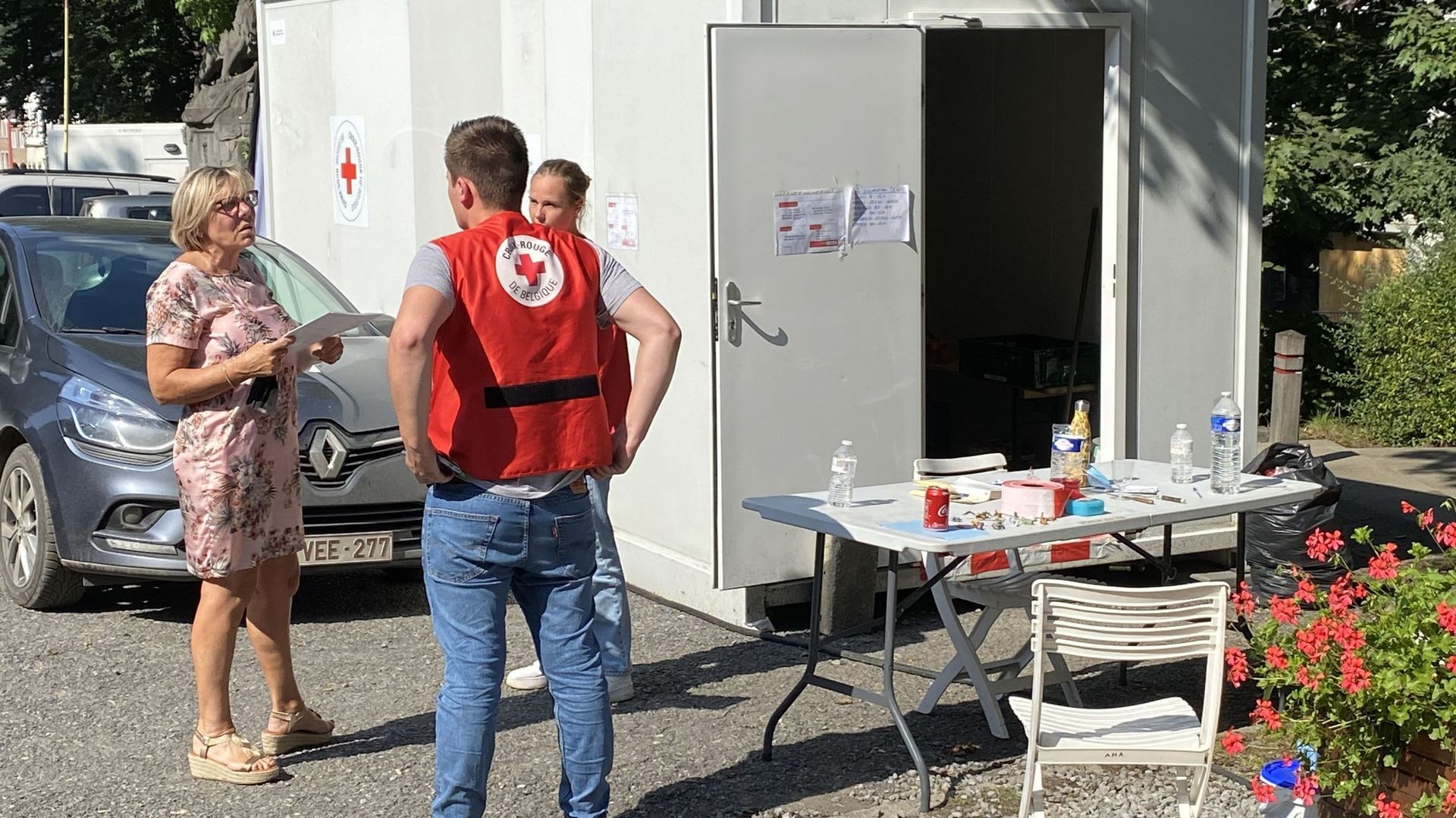 A Pepinster, deux bénévoles de la Croix Rouge discutent avec une femme en quête d'information