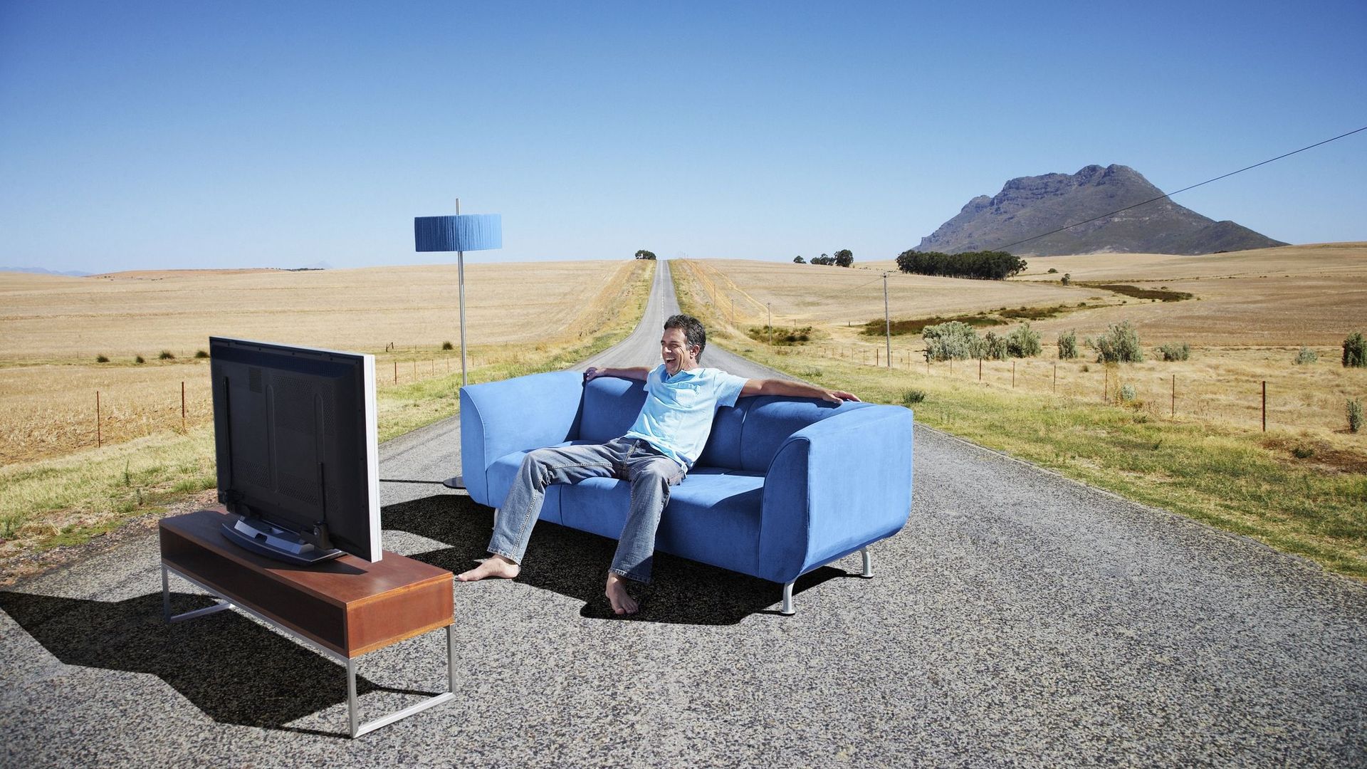 A man watching television on a couch in the road