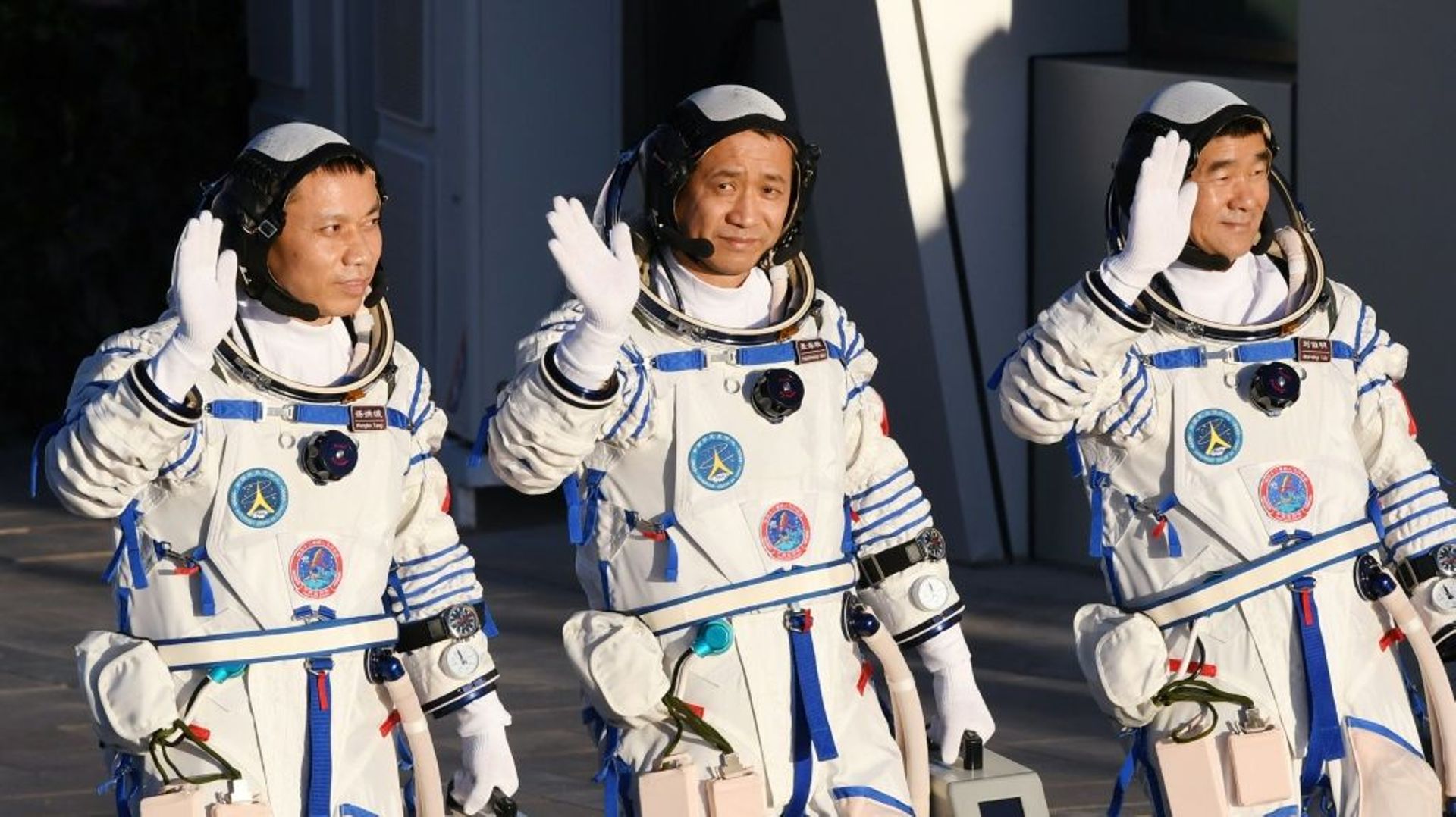 Les astronautes chinois Nie Haisheng (c), Liu Boming (d) et Tang Hongbo salue la foule avant leur décollage à bord de la fusée Longue-Marche 2F au Centre de lancement spatial de Jiuquan, le 17 juin 2021 en Chine