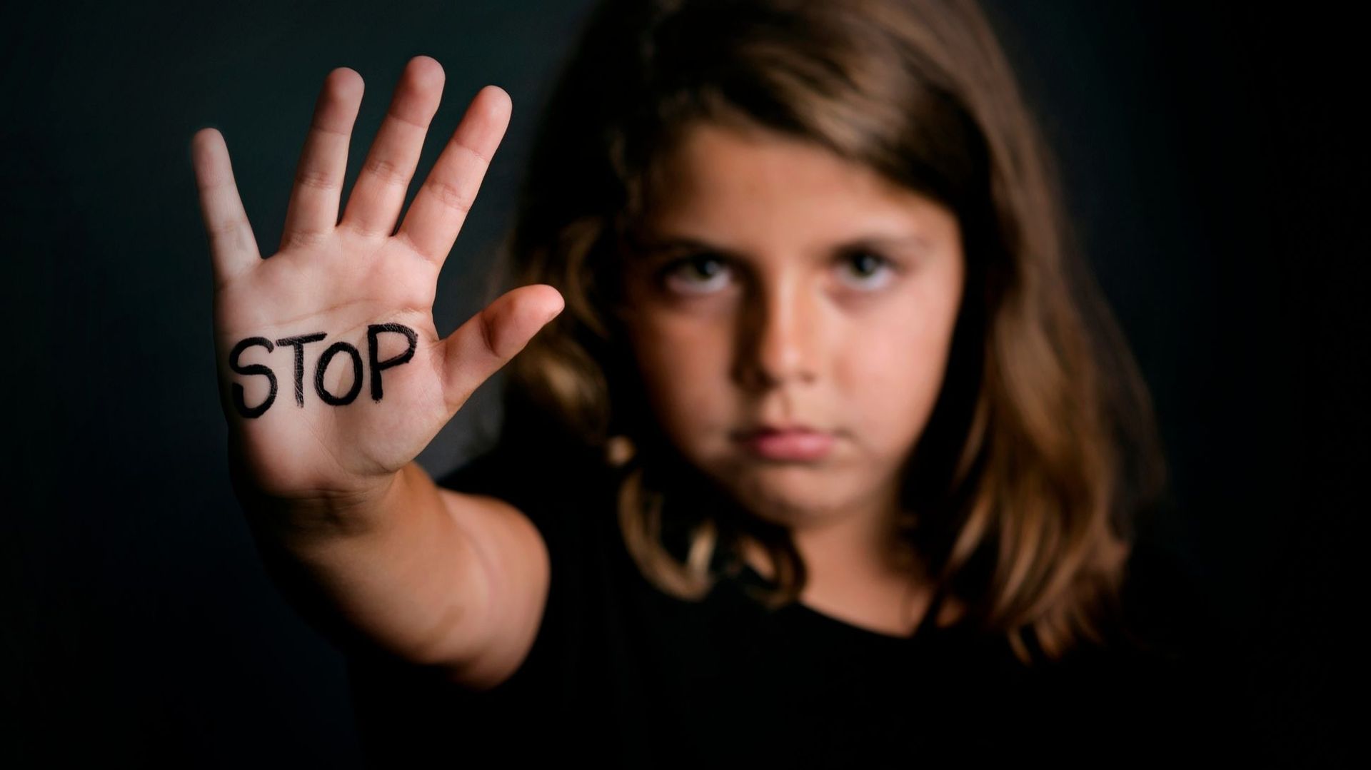 Une petite fille avec le mot STOP écrit sur la main. 