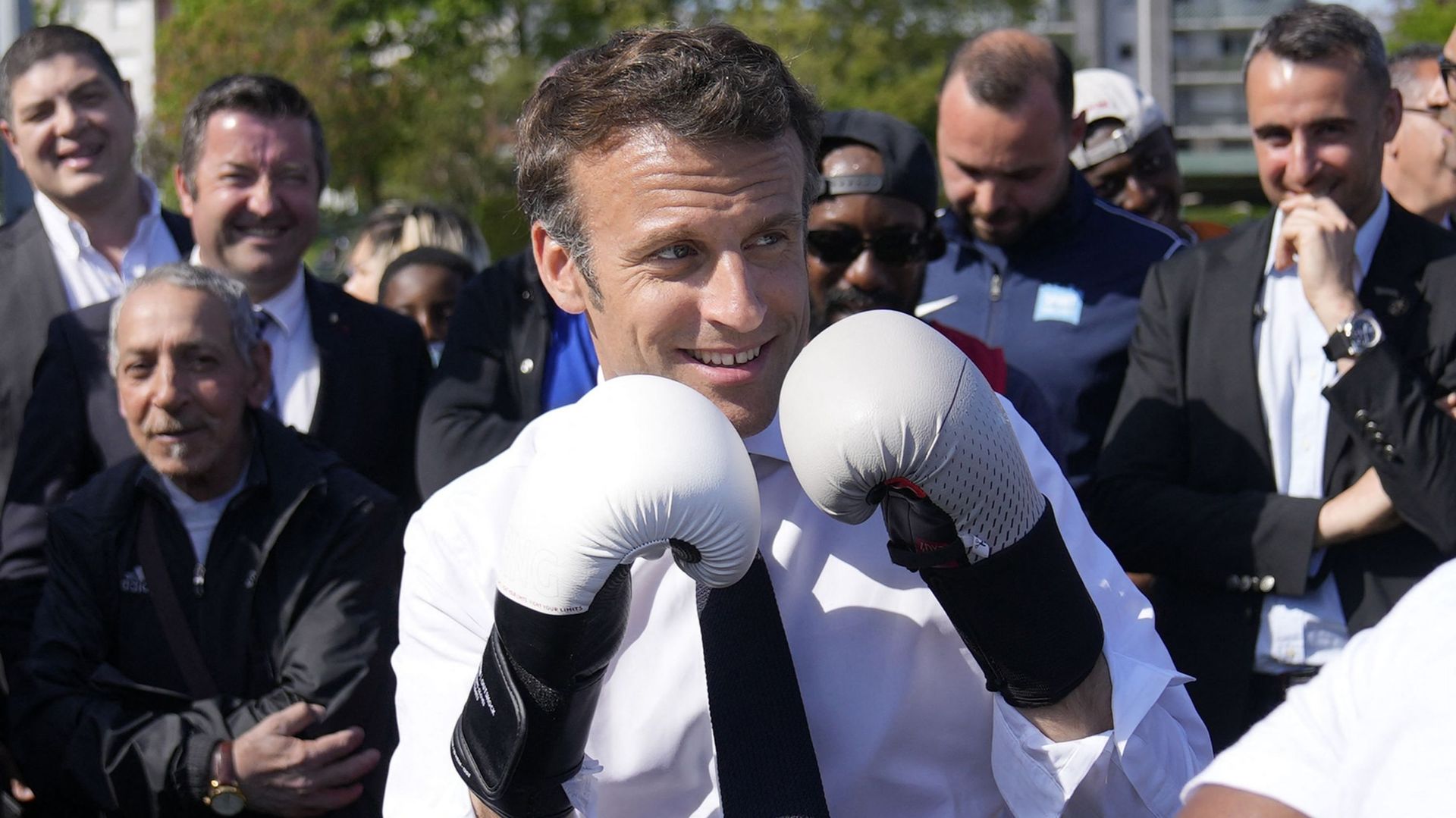 Le président-candidat Emmanuel Macron porte des gants de boxe alors qu'il rencontre un boxeur local au stade Auguste Delaune, le 21 avril 2022, lors d'une visite de campagne à Saint-Denis, en banlieue parisienne.