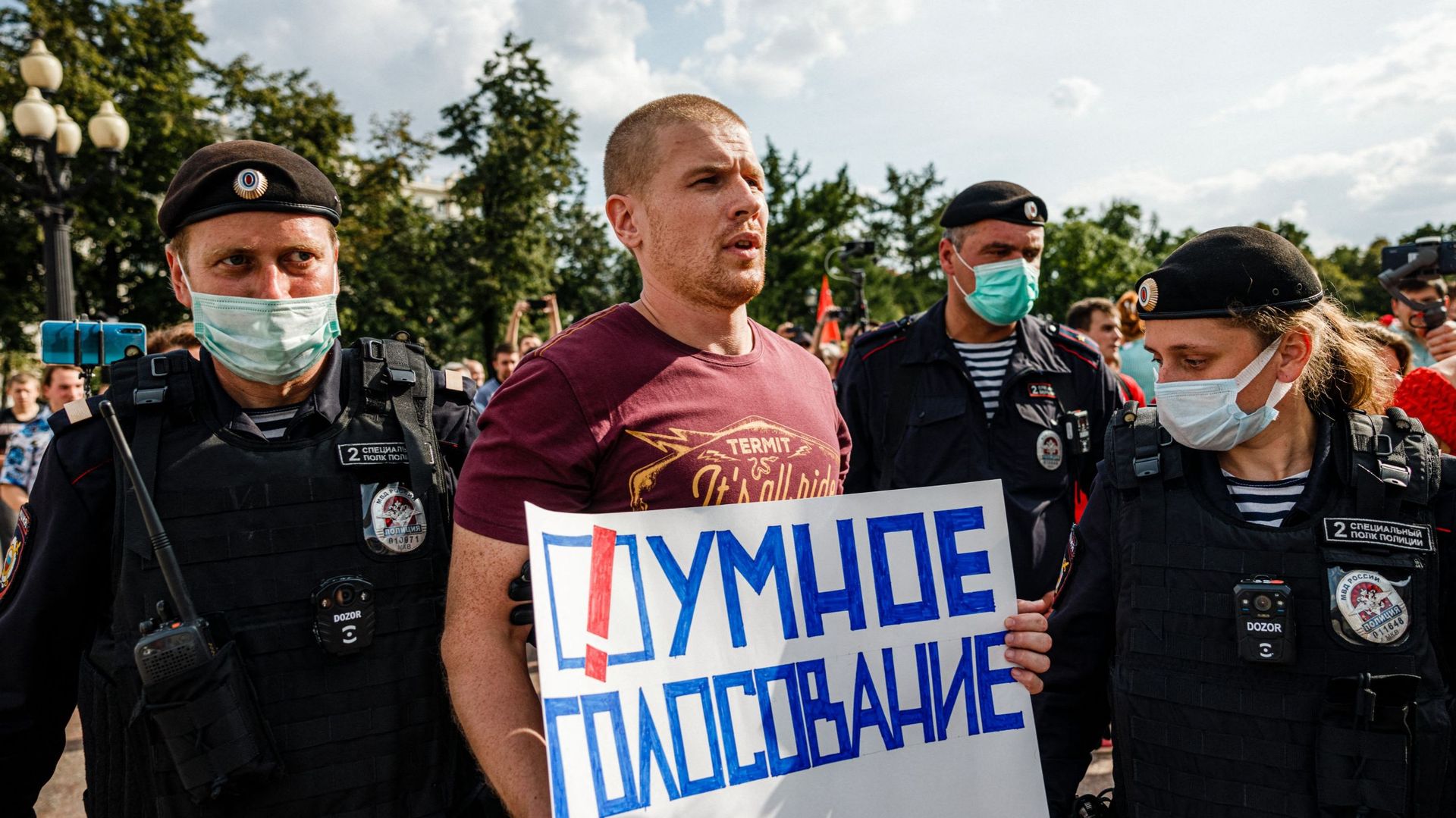 Des policiers arrêtent un homme avec une affiche sur laquelle on peut lire "Votez intelligemment" lors d’une manifestation anti-vaccination à Moscou, le 14 août 2021.