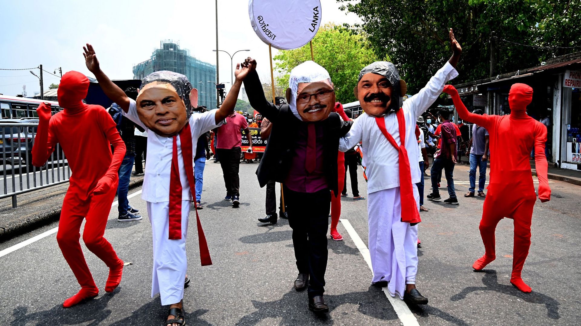 Des manifestants portant des masques à l’effigie de Gotabaya,  Mahinda et Basil Rajapaksa
