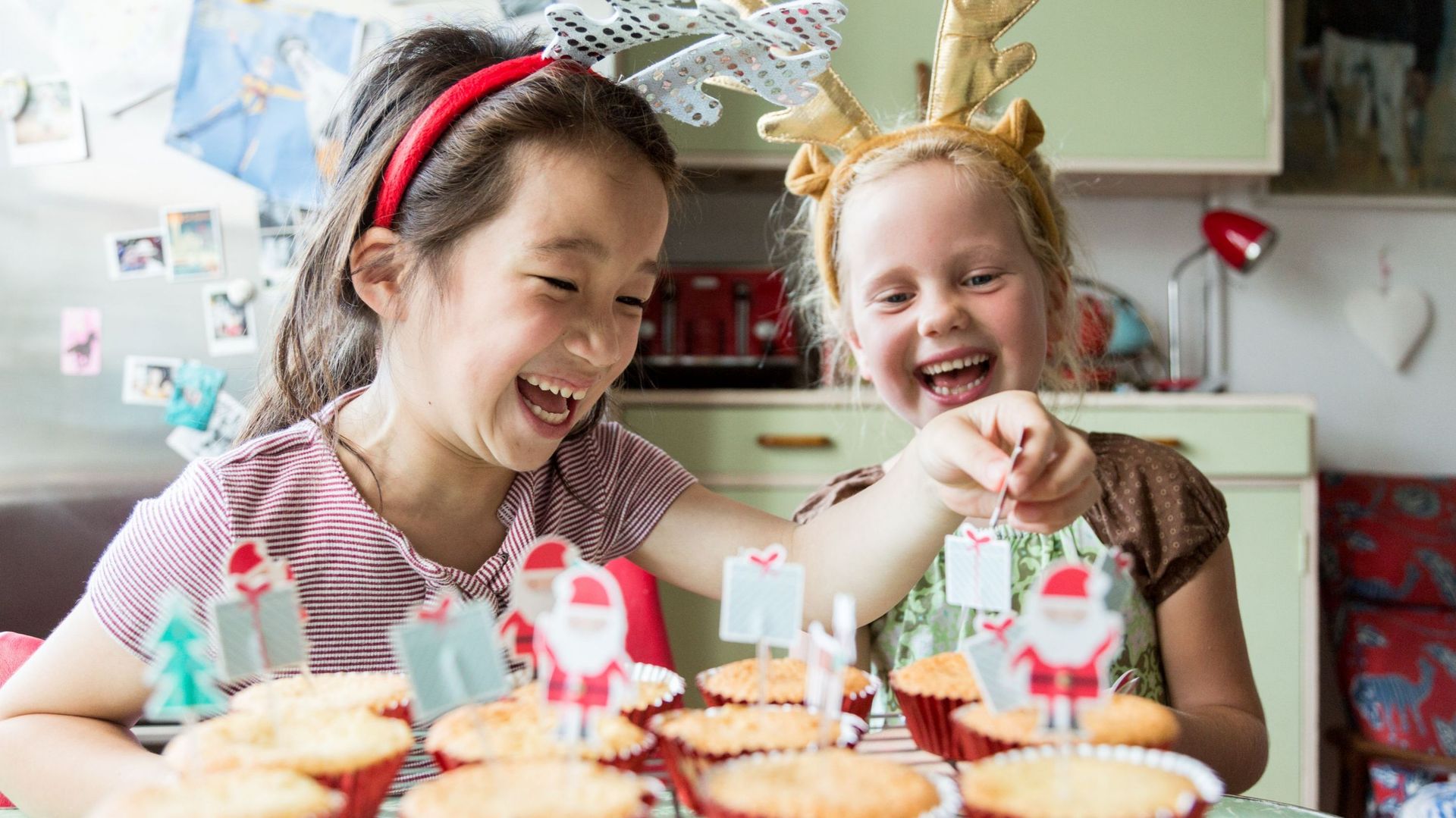 Girls laugh whilst decorating Christmas cupcakes