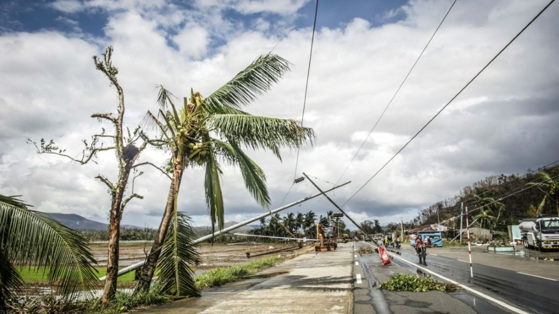 Des automobilistes passent devant des pylônes électriques arrachés le long d'une route à Surigao City, aux Philippines le 19 décembre 2021 après le passage du typhon Rai