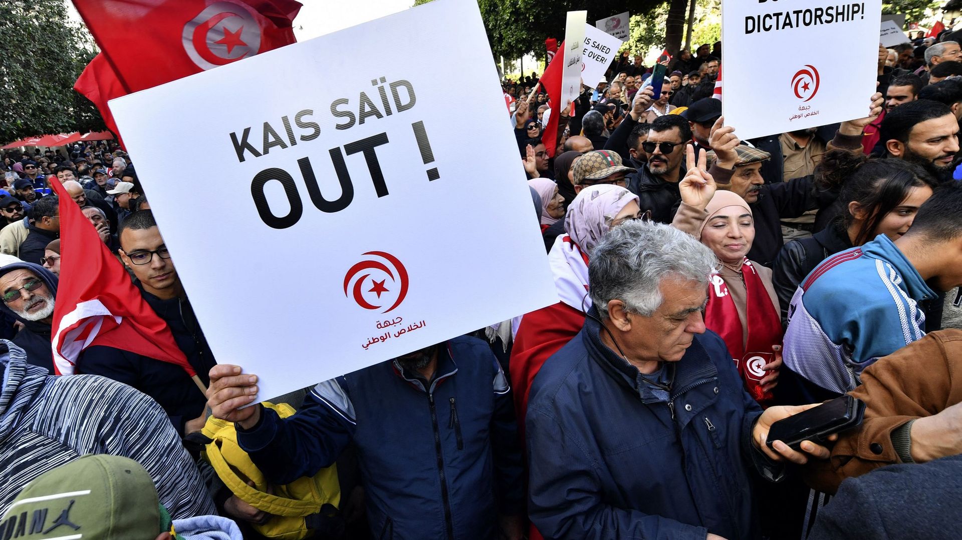 Des manifestants tunisiens portent des pancartes lors d’une manifestation dans le centre de Tunis contre leur président le 14 janvier 2023.