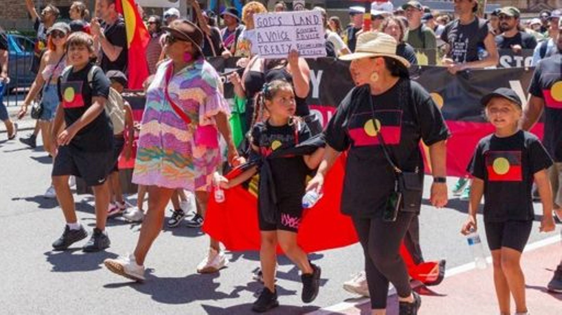 Des personnes tiennent une bannière alors qu’elles participent à la marche de protestation annuelle "Invasion Day" dans les rues de Sydney, le jour de l’Australia Day, le 26 janvier 2023.