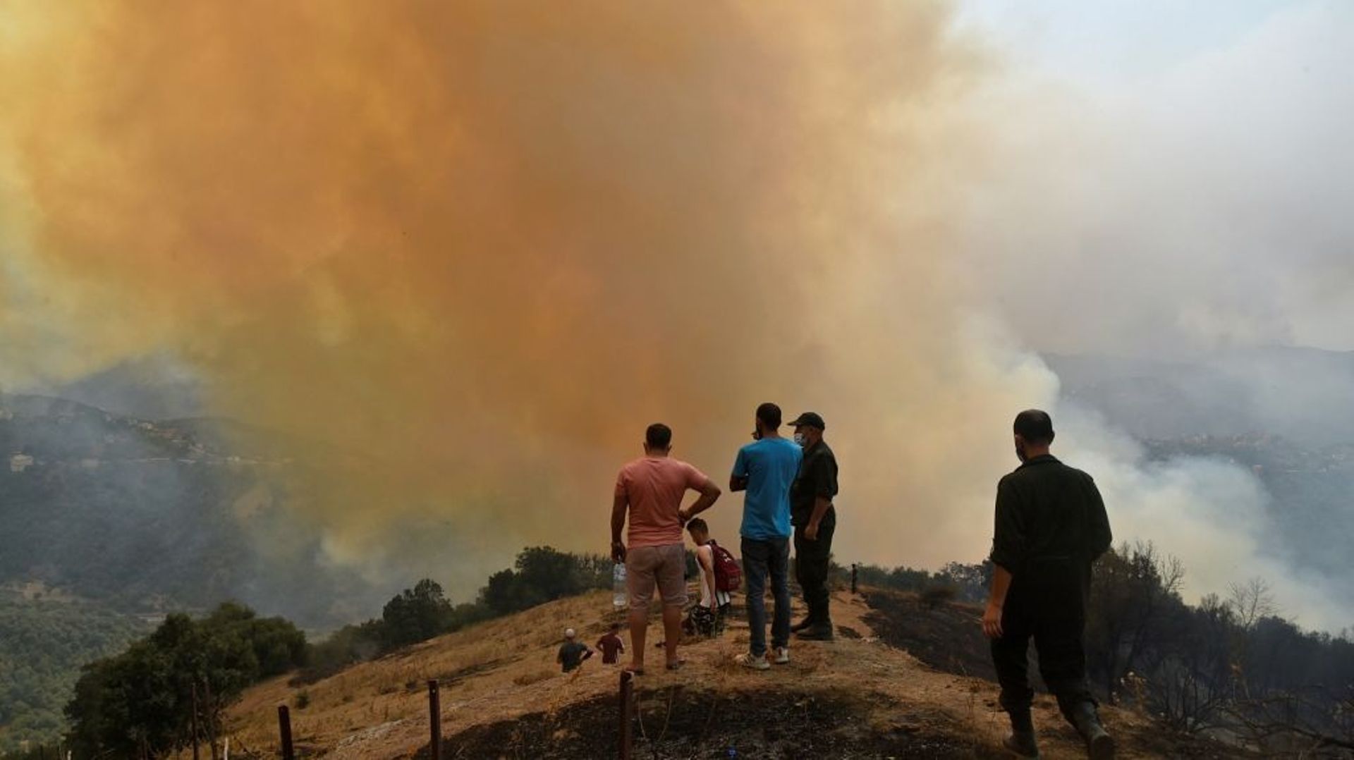 Des villageois observent un incendie en Kabylie, le 12 août 2021 en Algérie