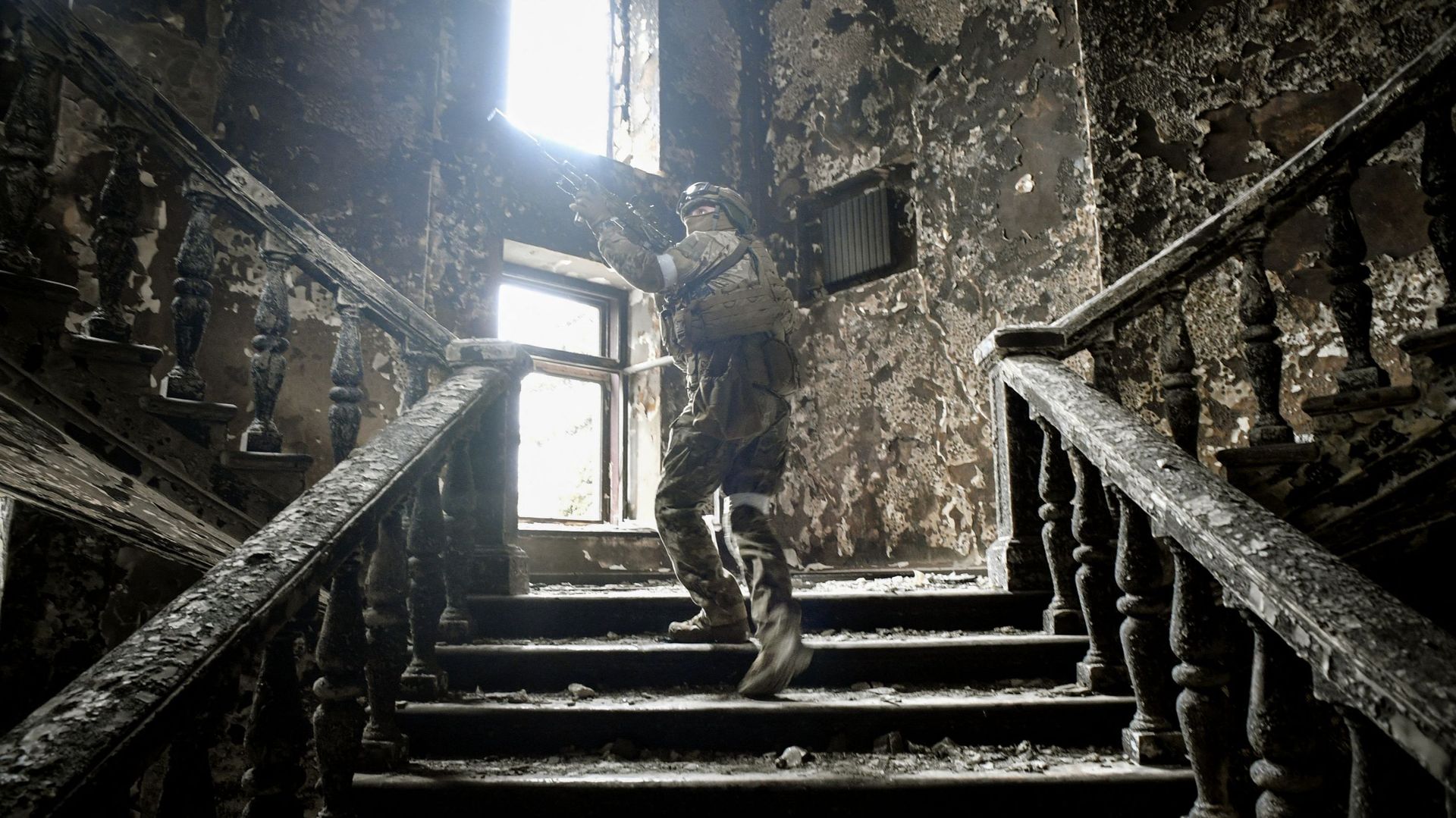 Un soldat russe monte les escaliers du théâtre de Mariupol, touché le 16 mars par une frappe aérienne, le 12 avril 2022 à Mariupol, alors que les troupes russes intensifient leur campagne pour prendre la ville portuaire stratégique, dans le cadre d’une at