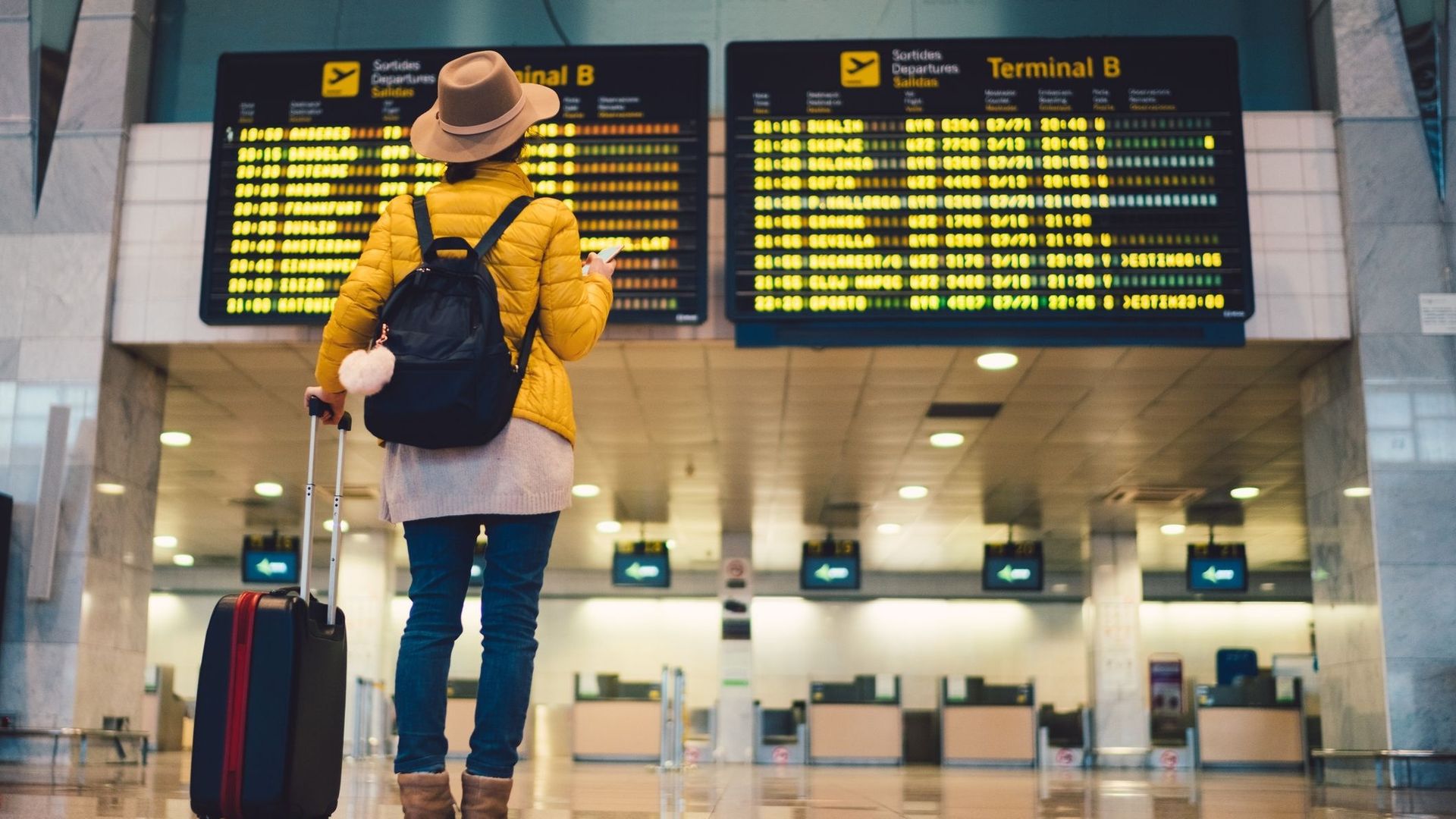 Jeune femme à l’aéroport de Barcelone vérifiant les horaires (illustration).