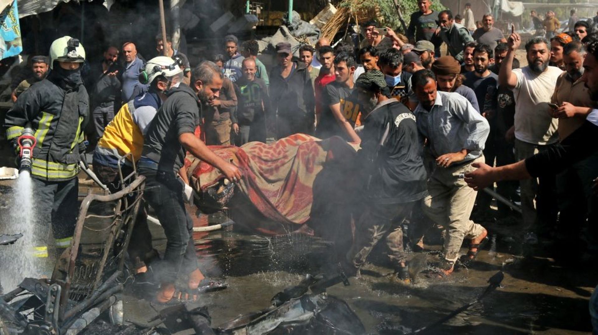Des sauveteurs évacuent le corps d'une victime après l'explosion d'une voiture piégée à Afrine, le 11 octobre 2021 en Syrie